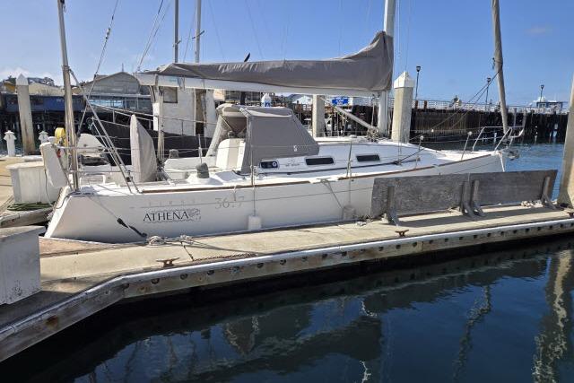 2002 Beneteau First 36.7 sailboat docked at a marina, featuring sleek design and covered sails.