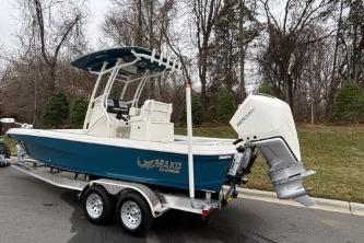2026 Mako 24 APEX boat on trailer, parked outdoors, with trees in the background.