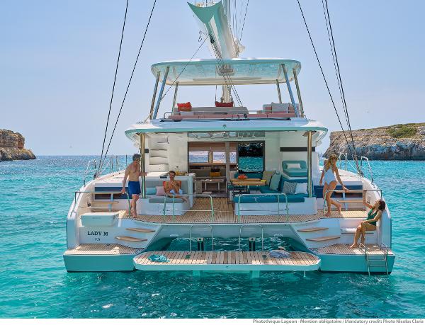 2025 Lagoon 55 yacht on turquoise water, featuring spacious deck and lounging area.