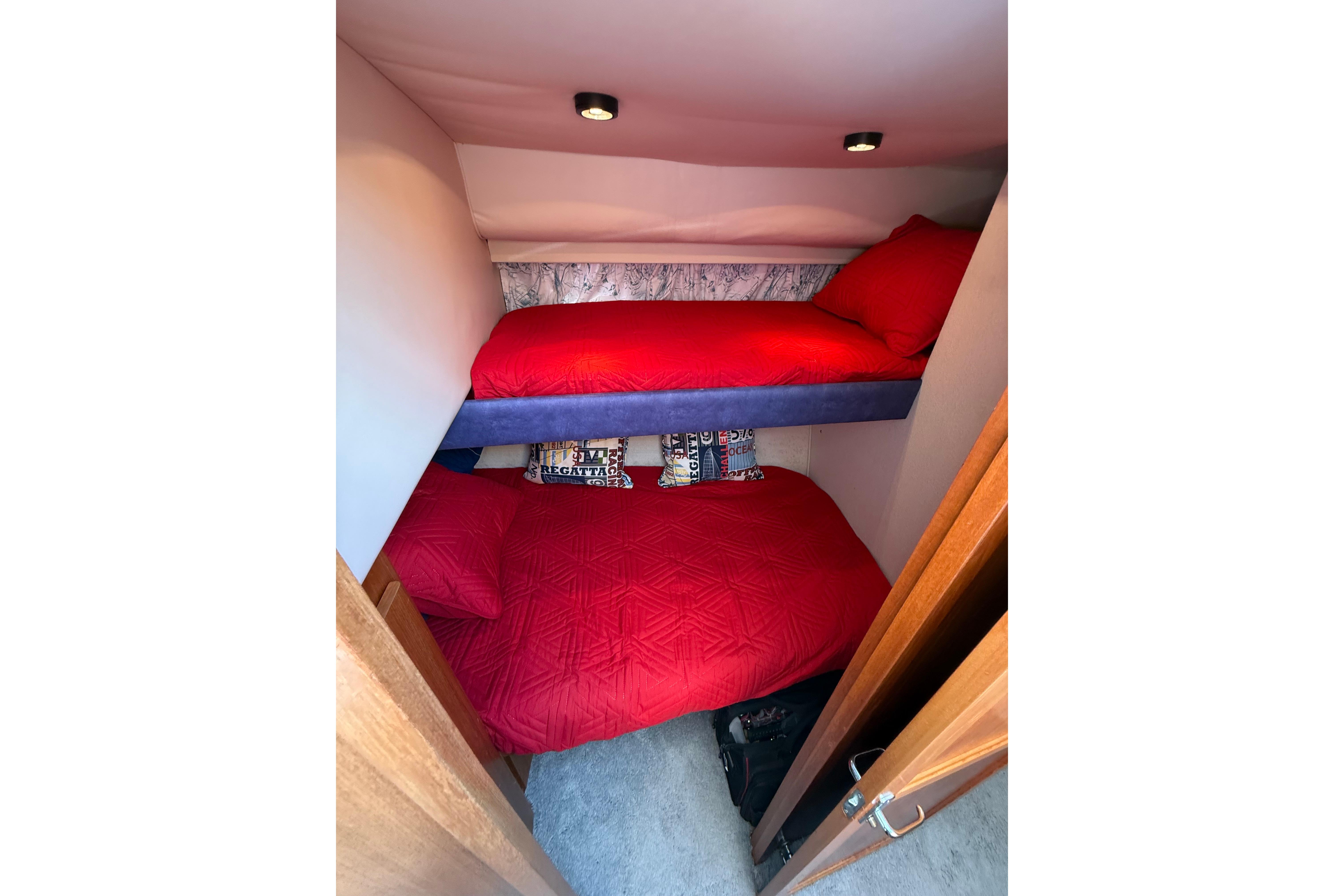 Bunk beds with red bedding in a 1995 Carver 370 Voyager cabin interior.