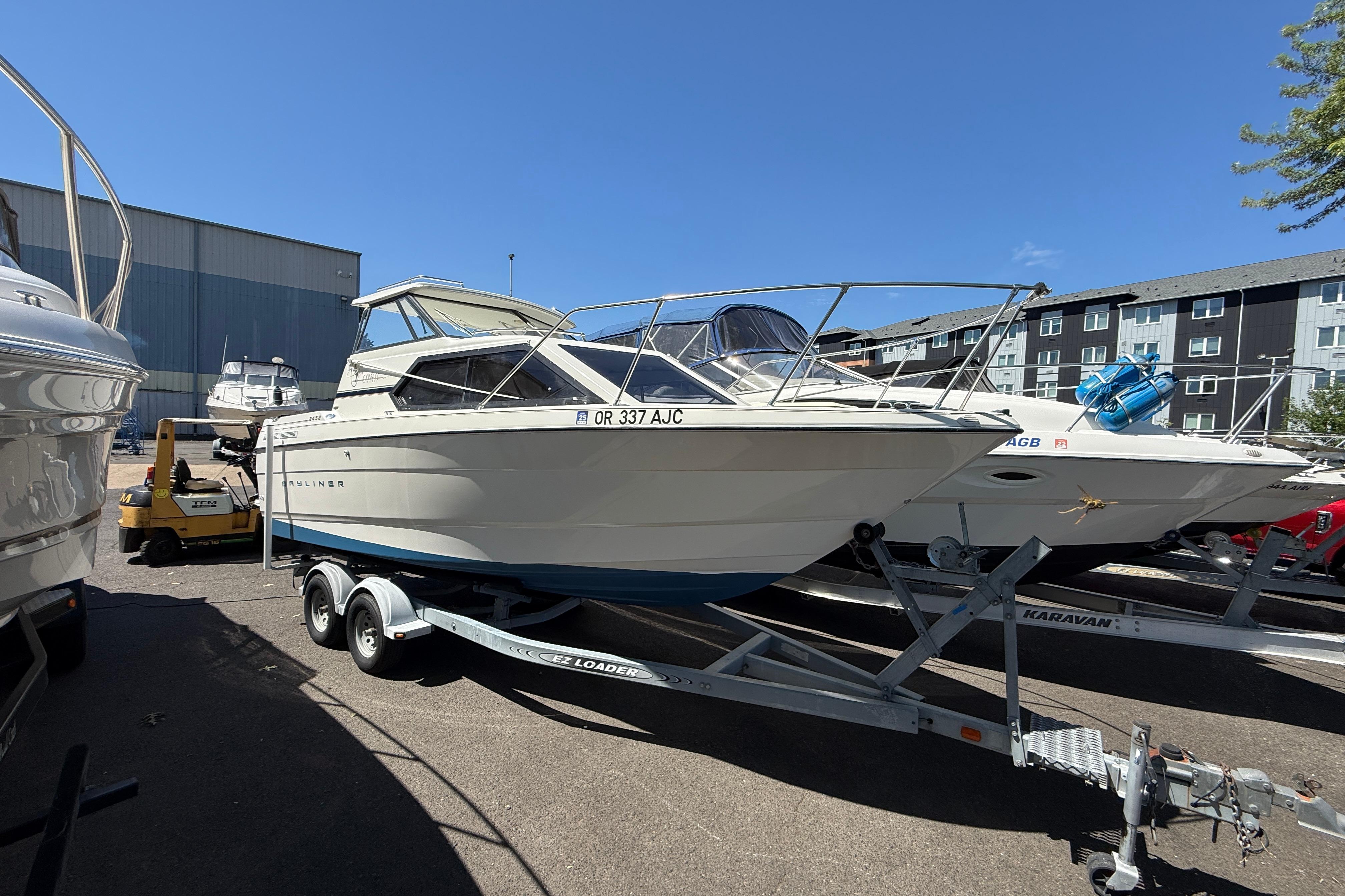 1997 Bayliner 2452 Ciera Express boat on trailer in marina parking lot.