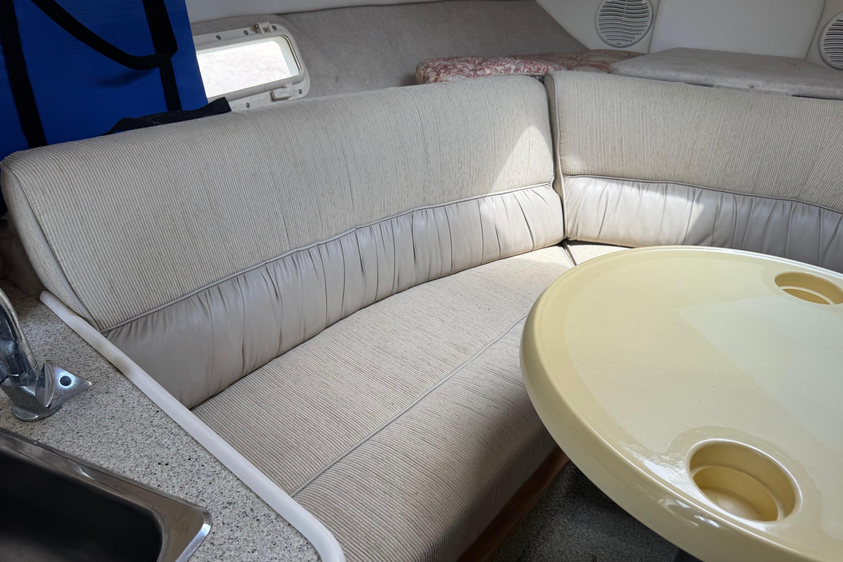 Interior of 2000 Maxum 2400 SCR boat with beige seating and round table.