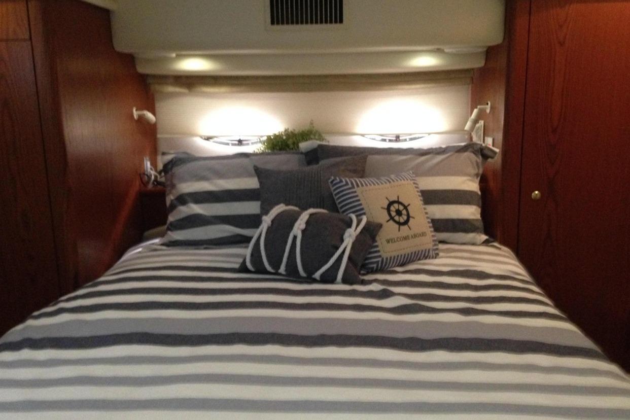 Cozy bedroom in 1999 Maxum 4100 SCA yacht with striped bedding and nautical decor.