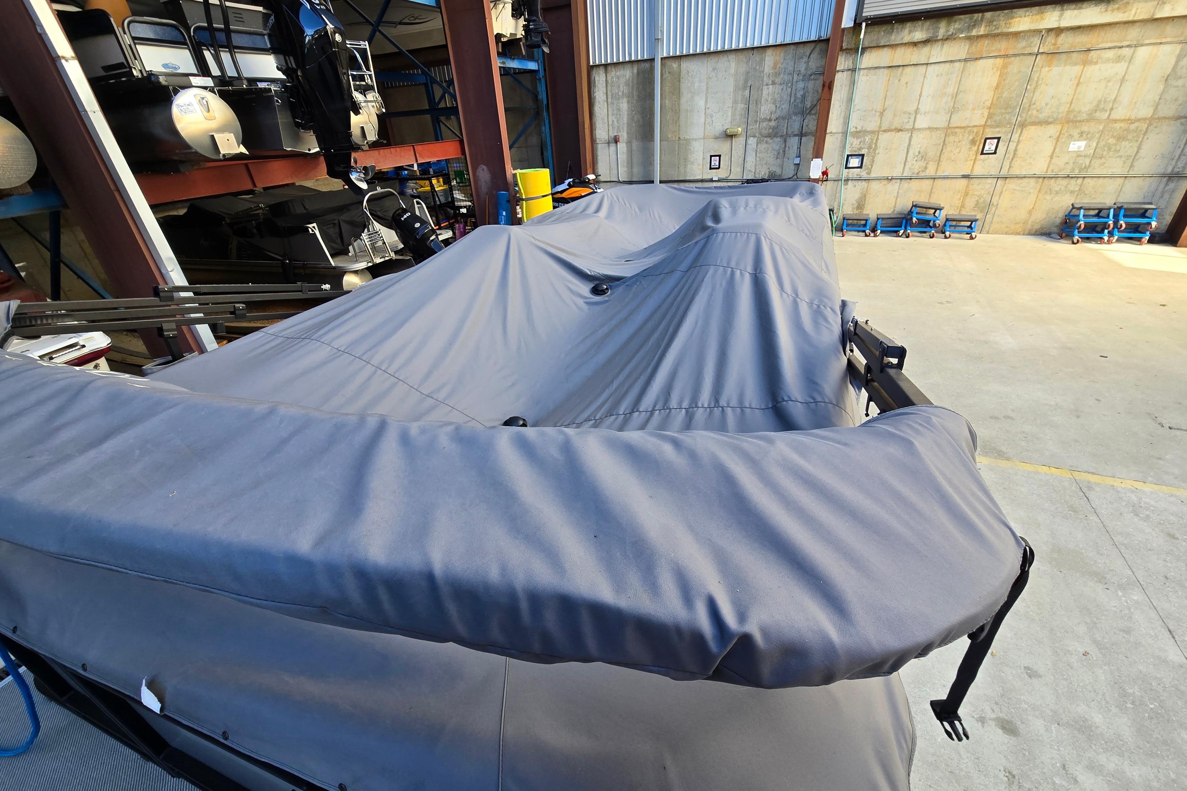 Covered 2024 Godfrey Sweetwater 2486 SB pontoon boat in storage facility.