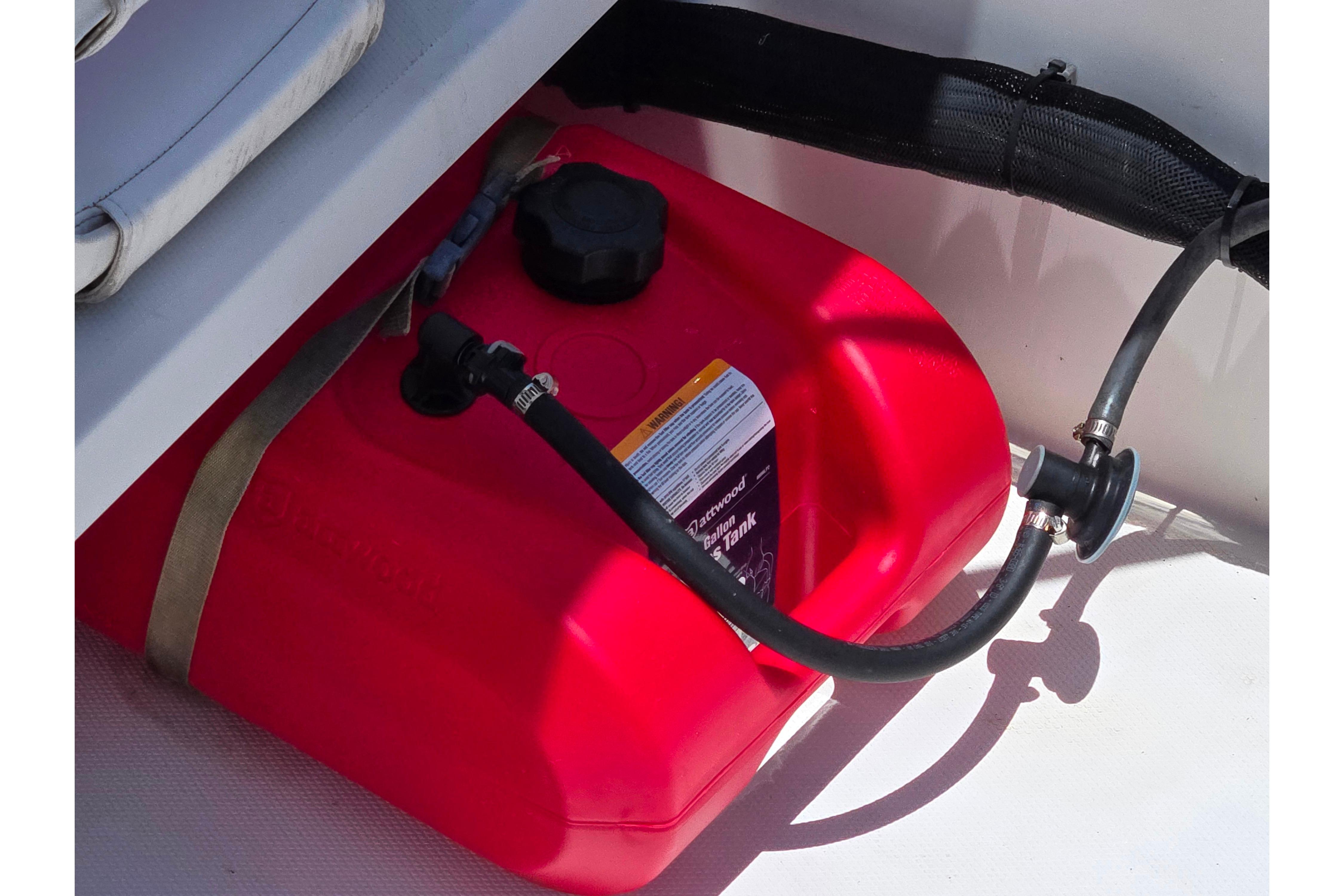Red fuel tank in a 2014 Boston Whaler 13 SS boat, secured with a strap.