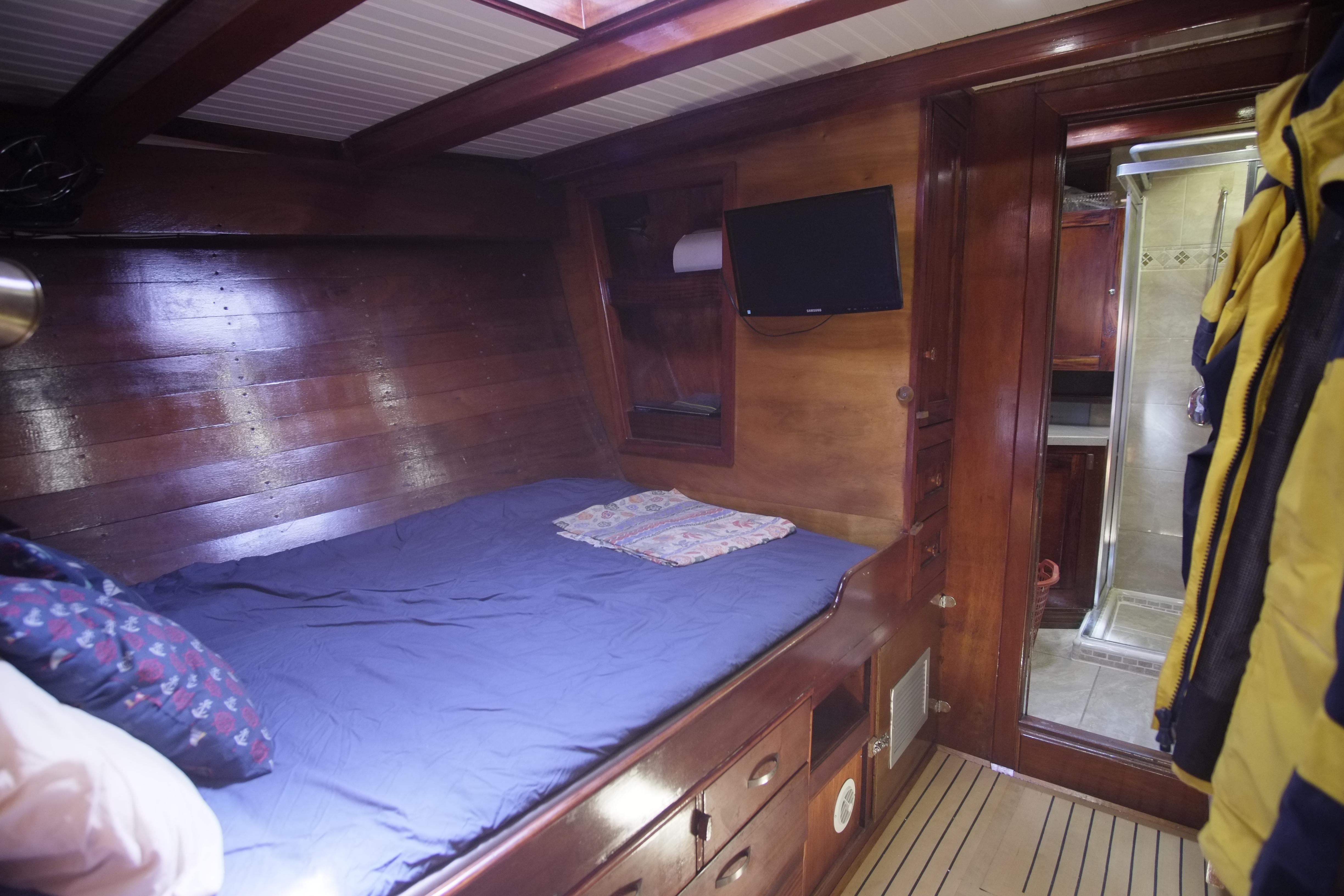 Cozy wooden cabin interior of 2006 Custom Bud Macintosh schooner with bed and TV.