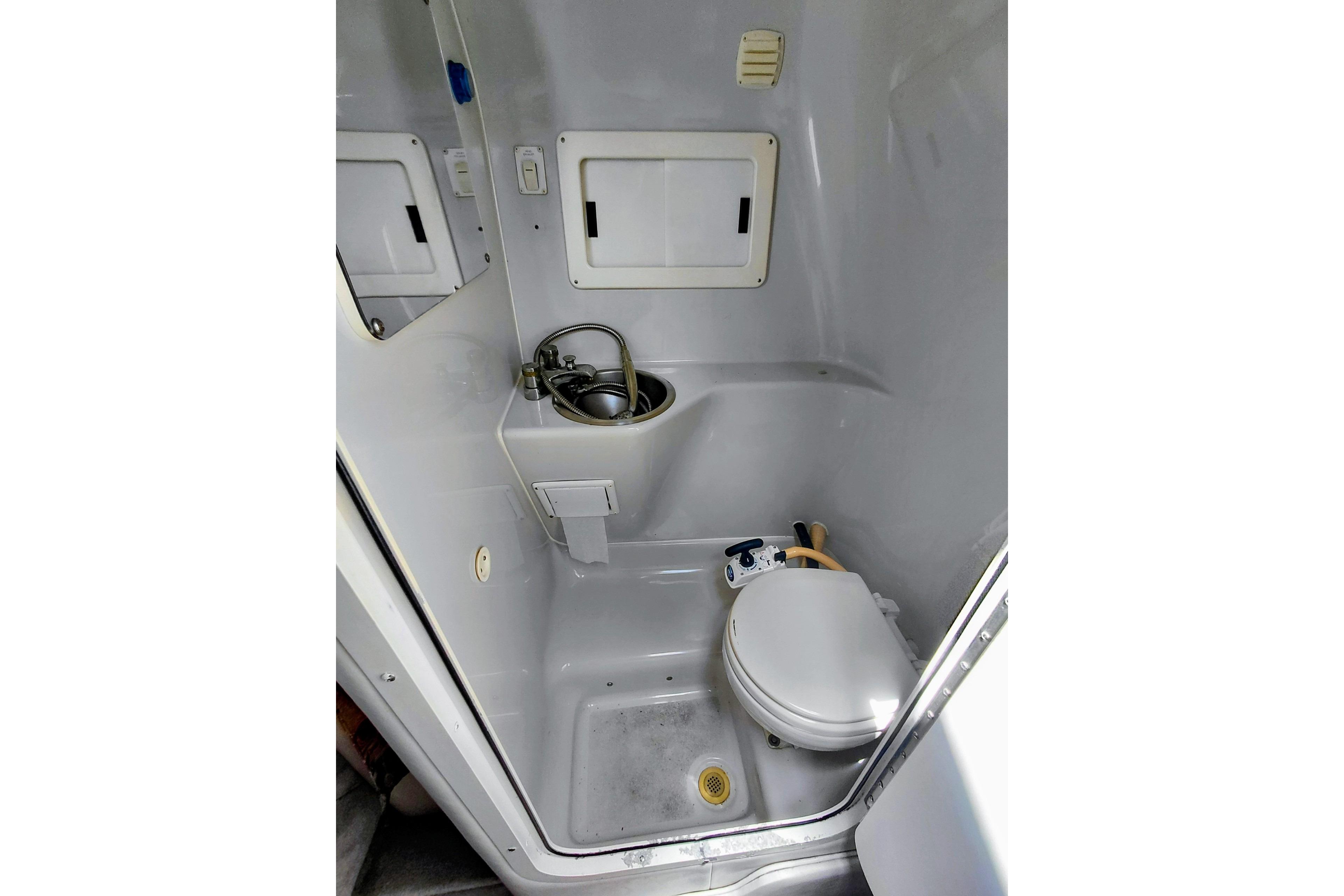 Compact bathroom in 2000 Crownline 242 CR boat, featuring toilet and sink.