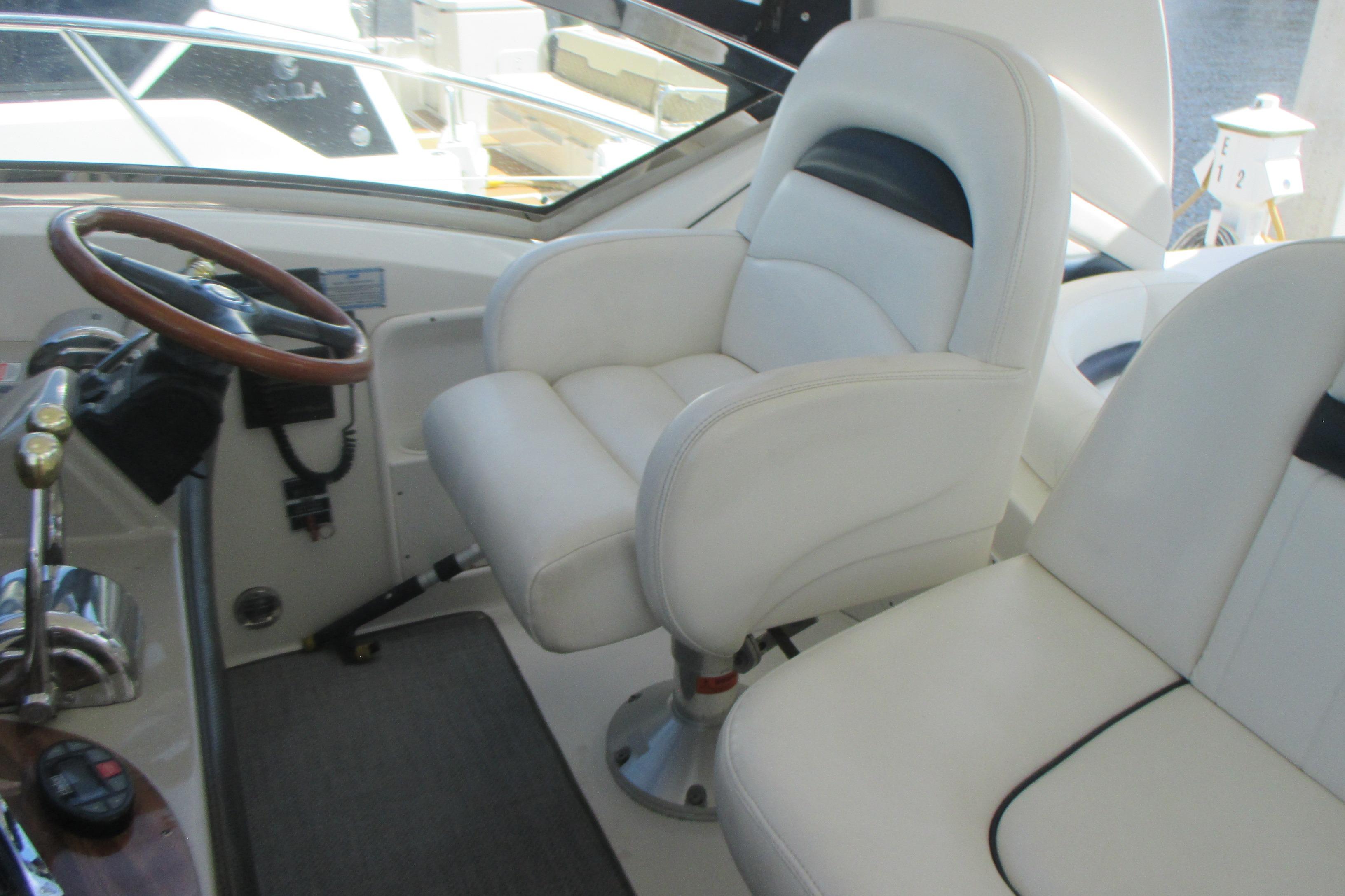 Helm of 2005 Sea Ray 390 Sundancer with white captain's chair and wooden steering wheel.