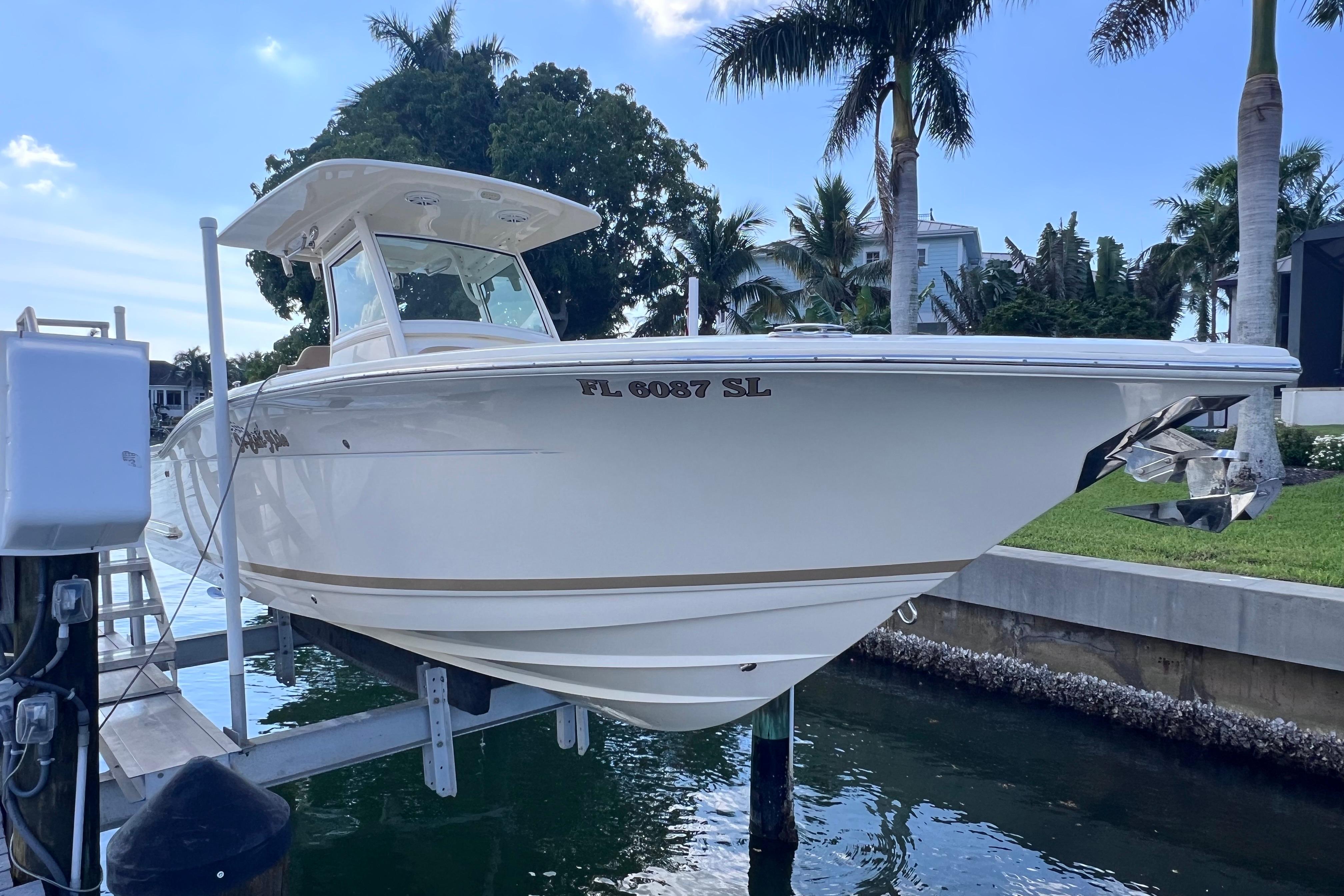 2019 Scout 275 LXF boat docked near palm trees and waterfront homes.