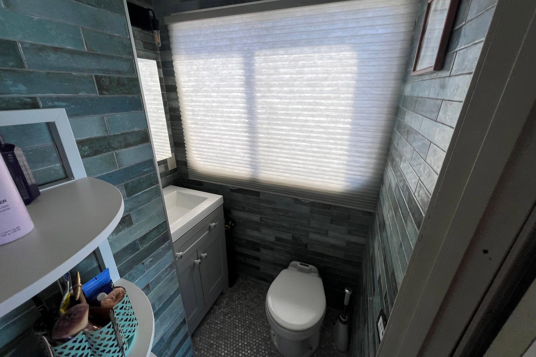 Bathroom interior of a 1993 Sumerset houseboat with teal tiles and modern fixtures.