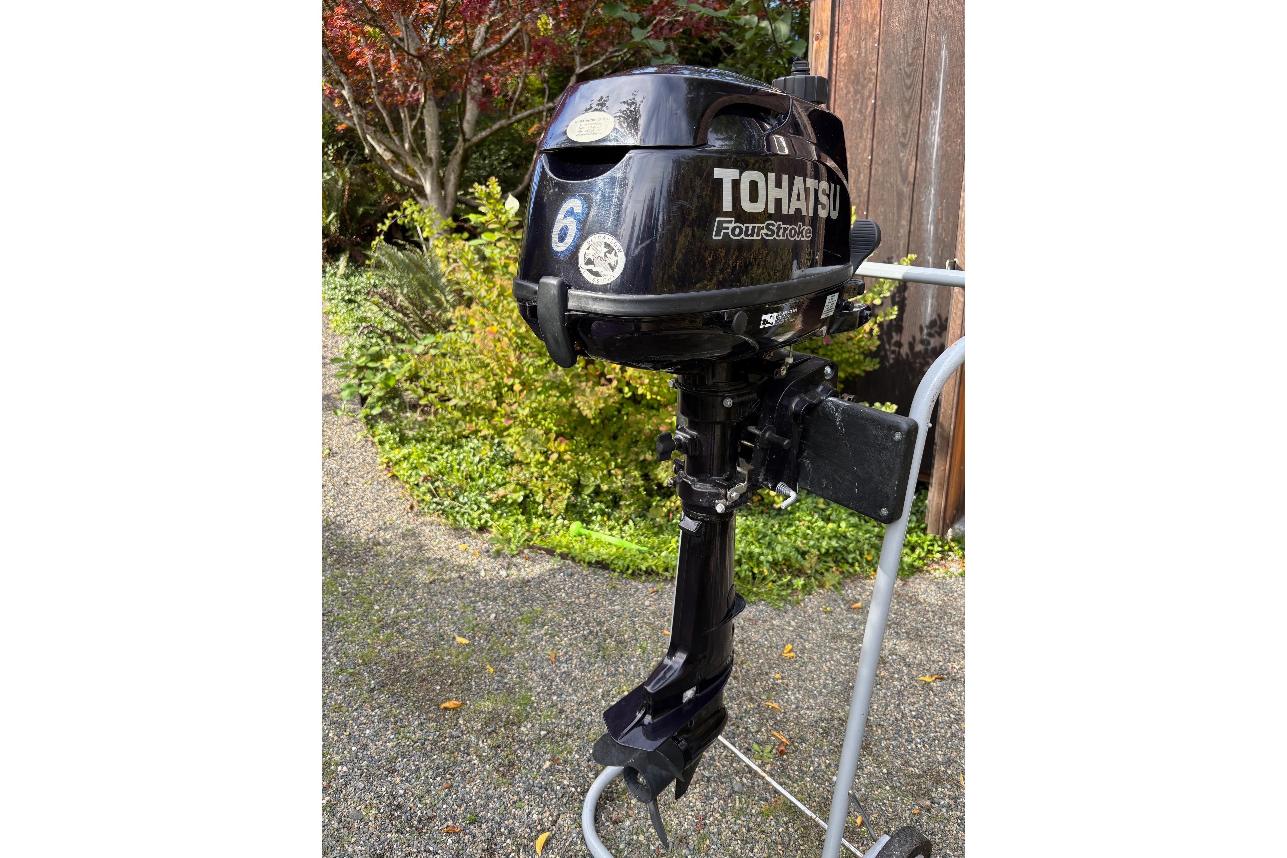 Tohatsu 6HP Four-Stroke outboard motor on stand, garden background.