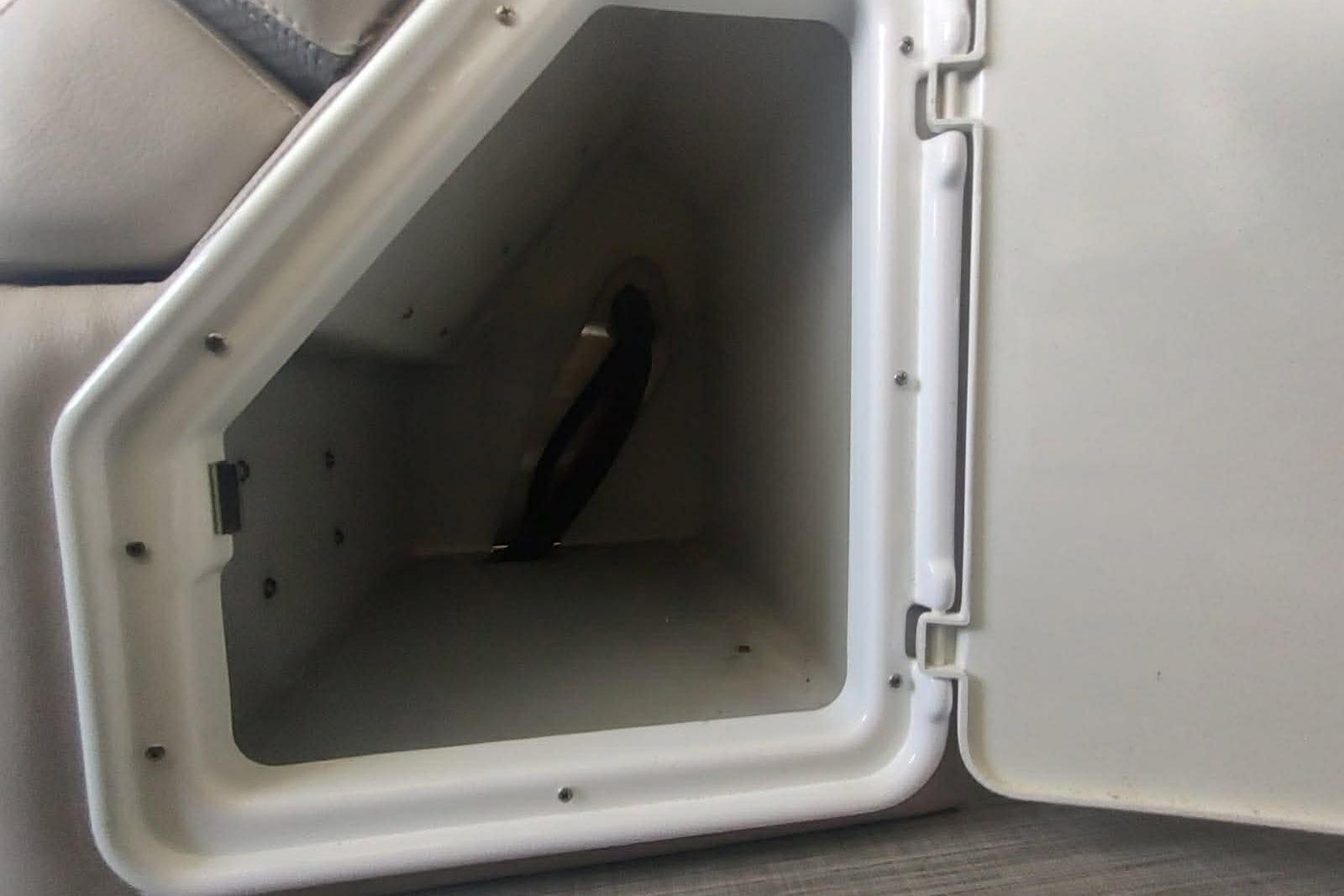 Storage compartment in 2023 PlayCraft 27 Infinity boat, featuring a white interior and secure latch.