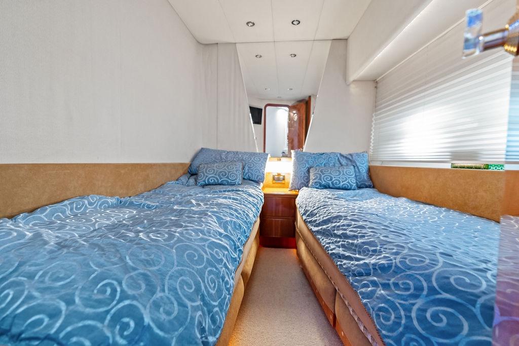 Interior of 1999 Azimut 58 yacht with twin beds and blue bedding.