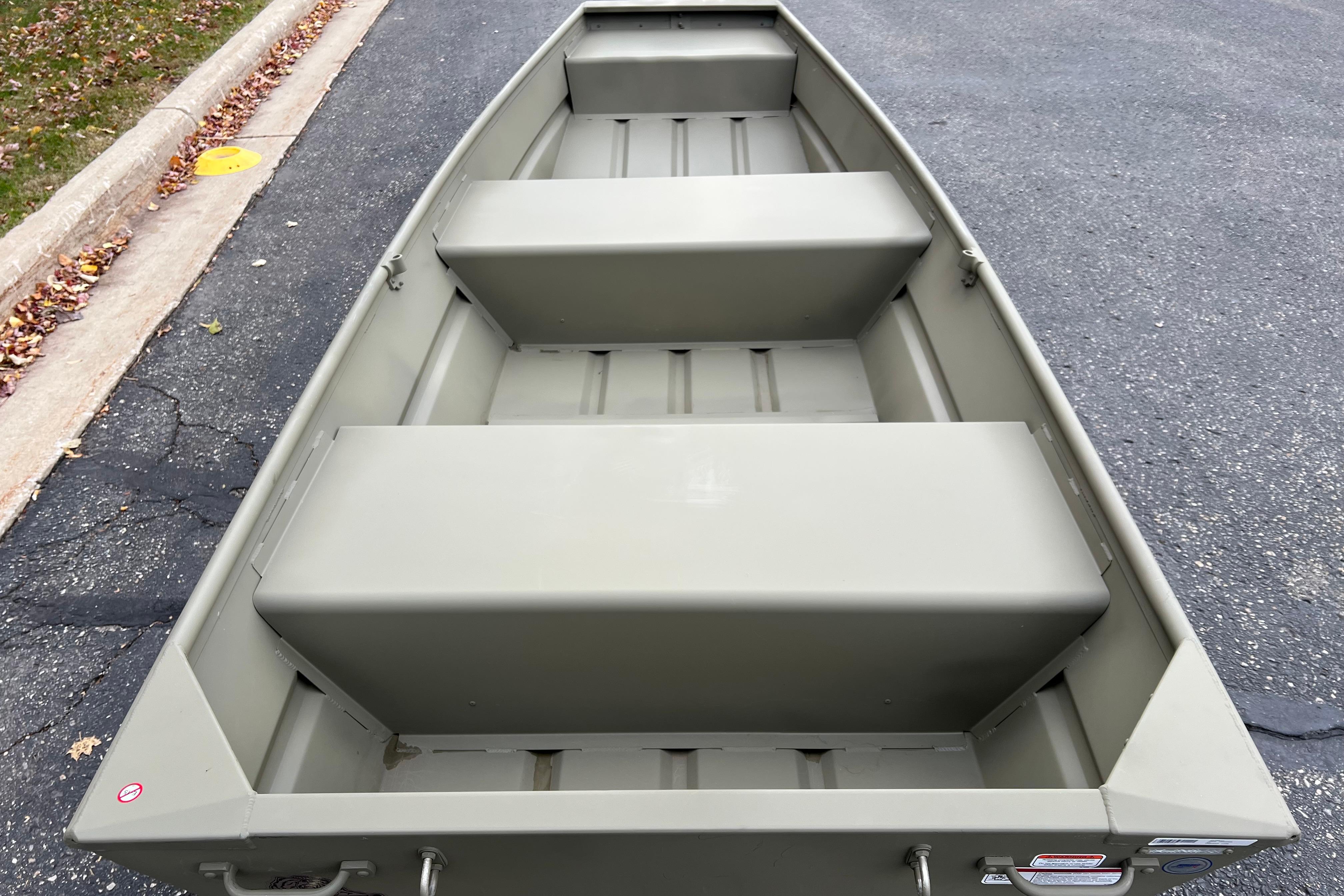 2026 Tracker Grizzly 12 Jon boat on pavement, showcasing interior seating and design.