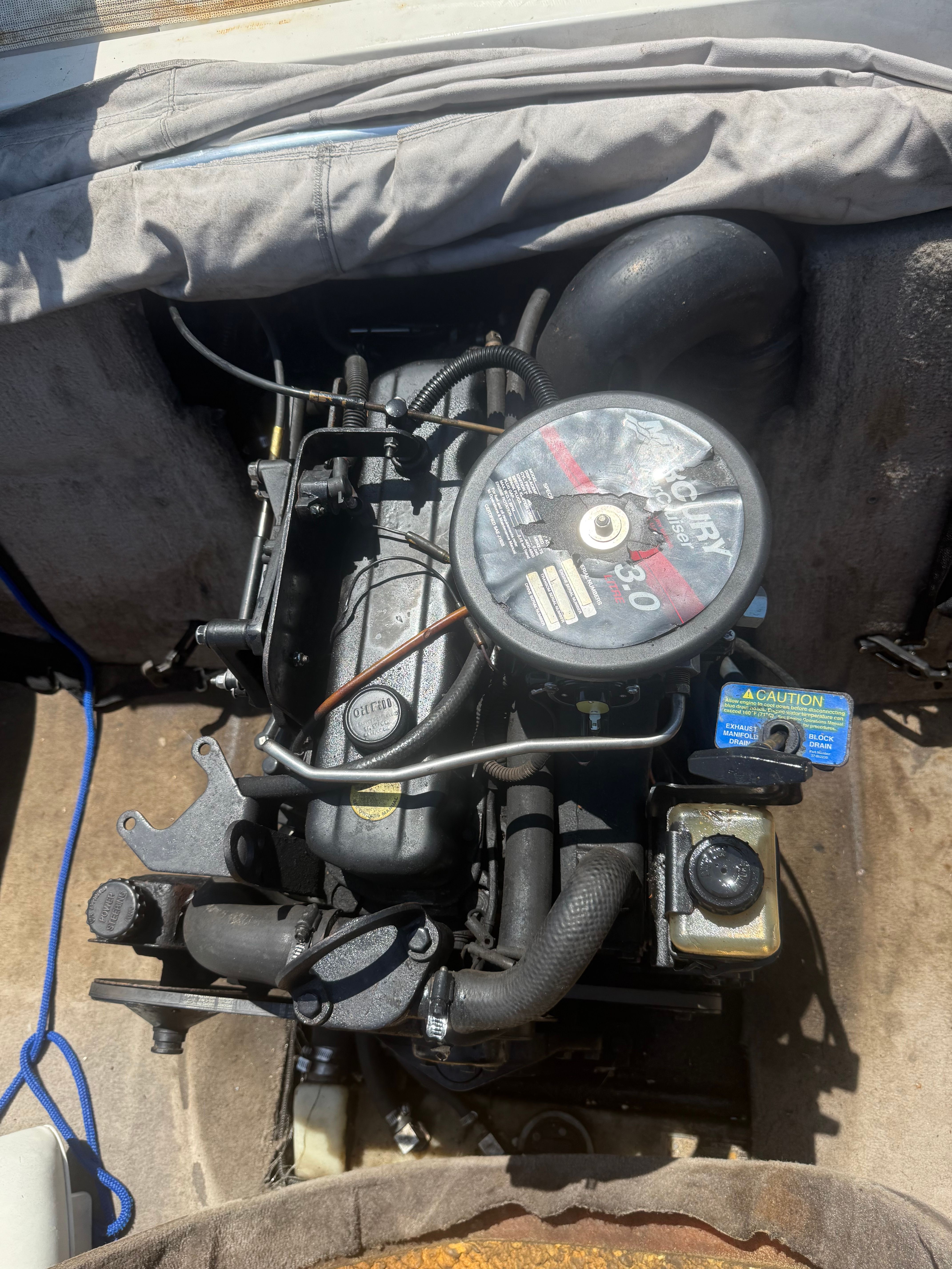Boat engine compartment with a motor and various hoses and cables.
