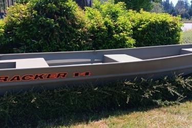 2026 Tracker Grizzly 14 Jon boat displayed outdoors near greenery.