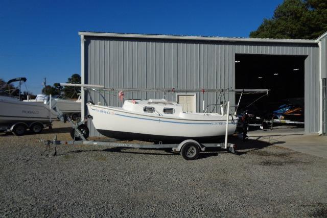 2007 Sanibel 18 Pocket Cruiser sailboat on trailer outside metal storage building.