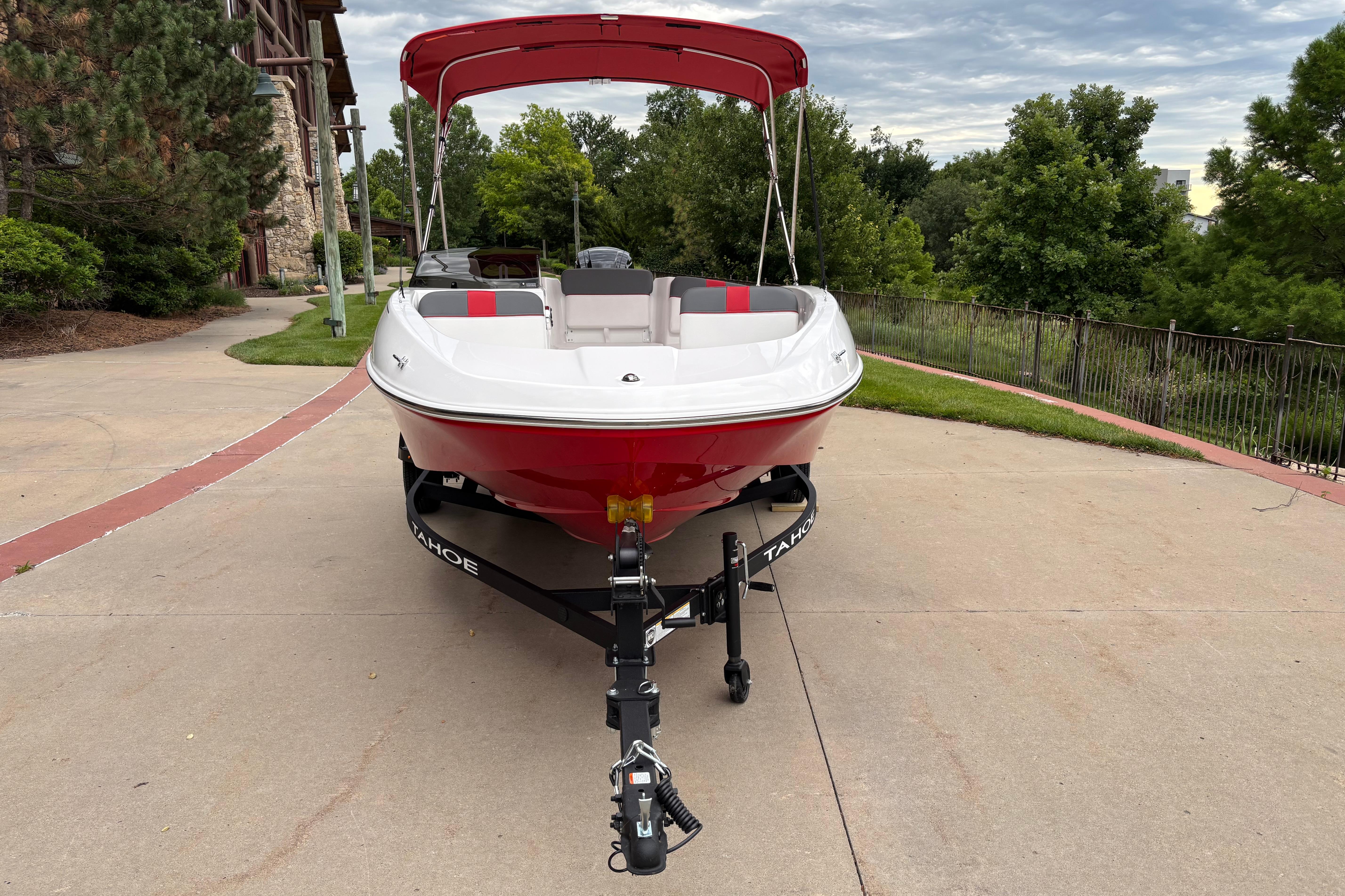 2026 Tahoe T16 boat with red canopy on a trailer, parked outdoors.