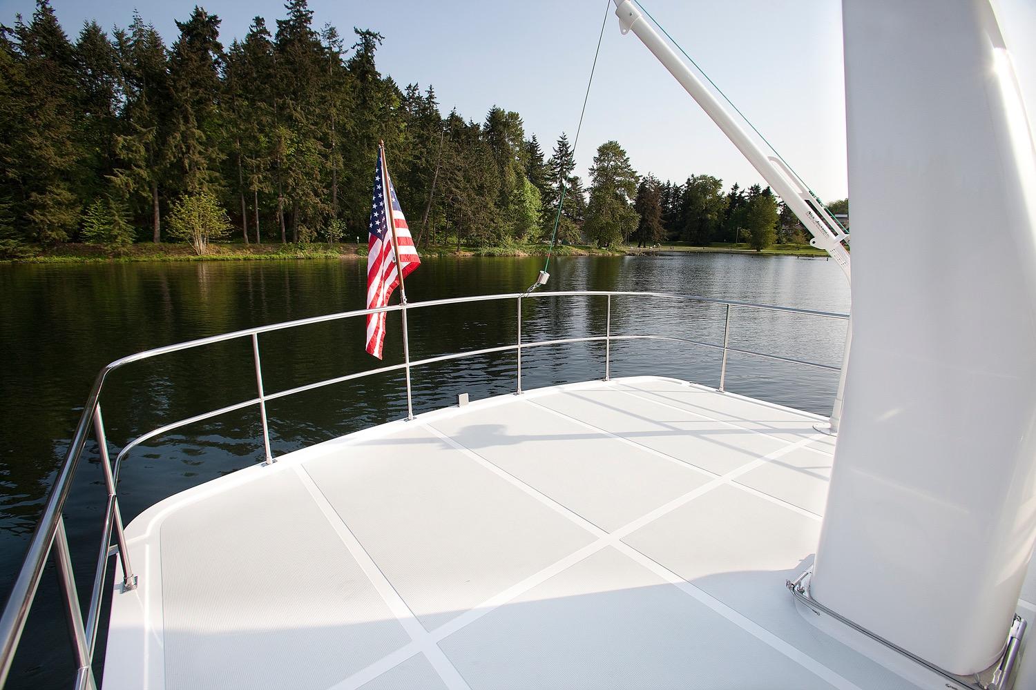 Helmsman Trawlers 43 Pilothouse 2026 yacht deck with American flag, serene lake view.
