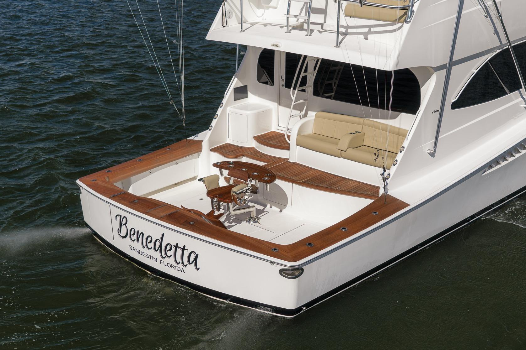 2012 Viking 70 Enclosed Bridge yacht, rear view, on water, featuring teak deck and seating.