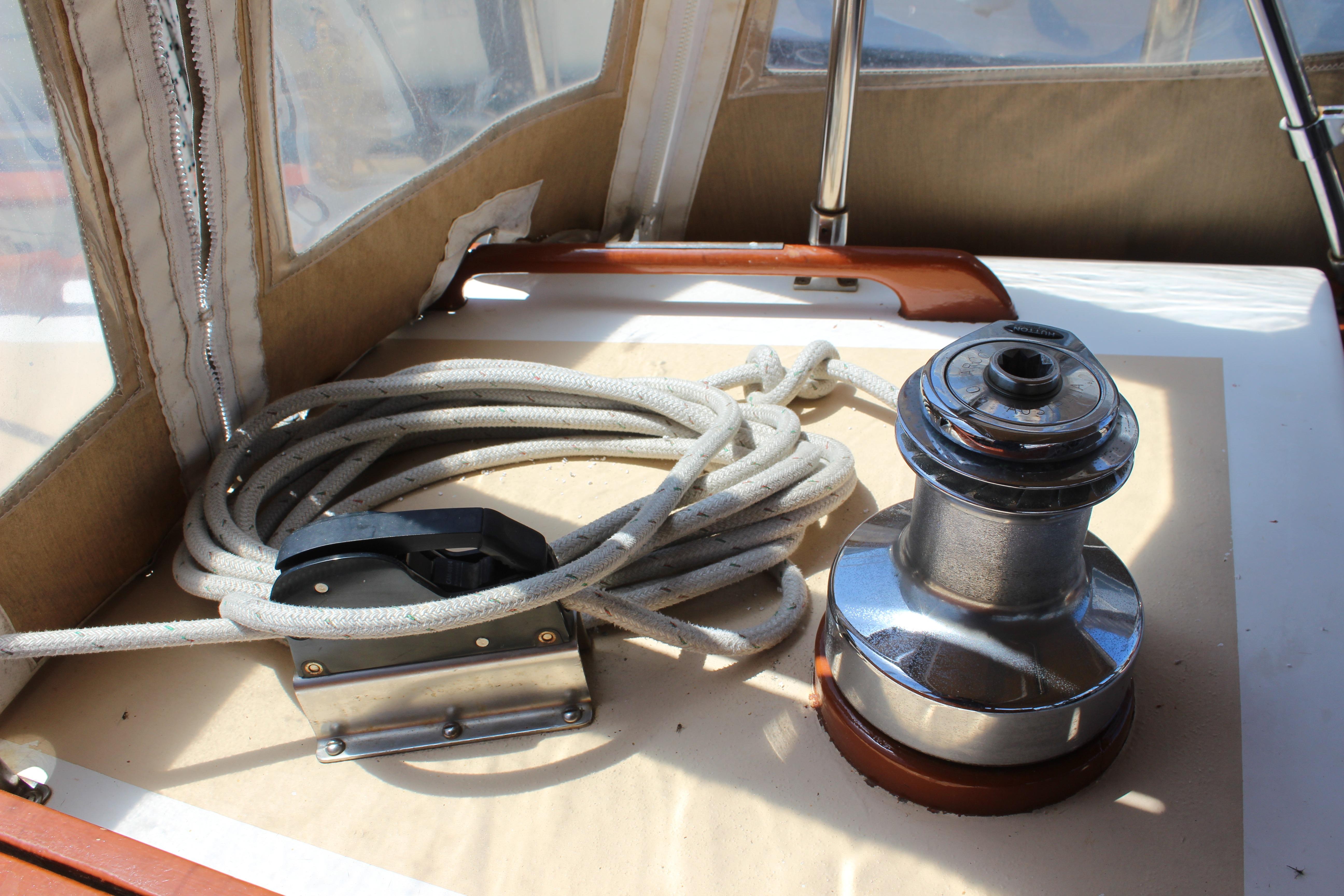 Winch and rope on 1981 Kelly Peterson 46 sailboat deck, under sunlight.