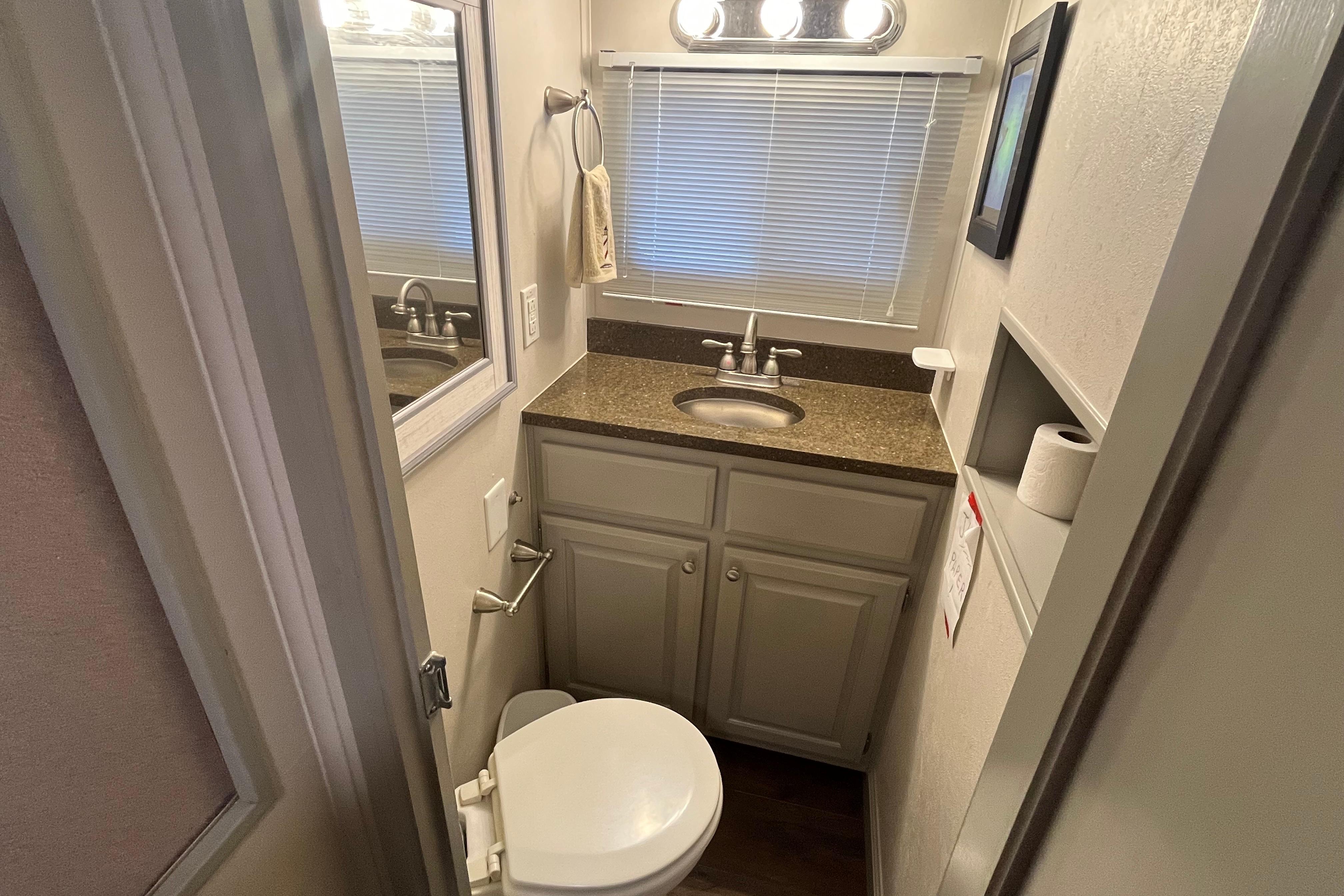 Compact bathroom in 1995 WaveLenth Wide Body RV with sink, toilet, and storage.
