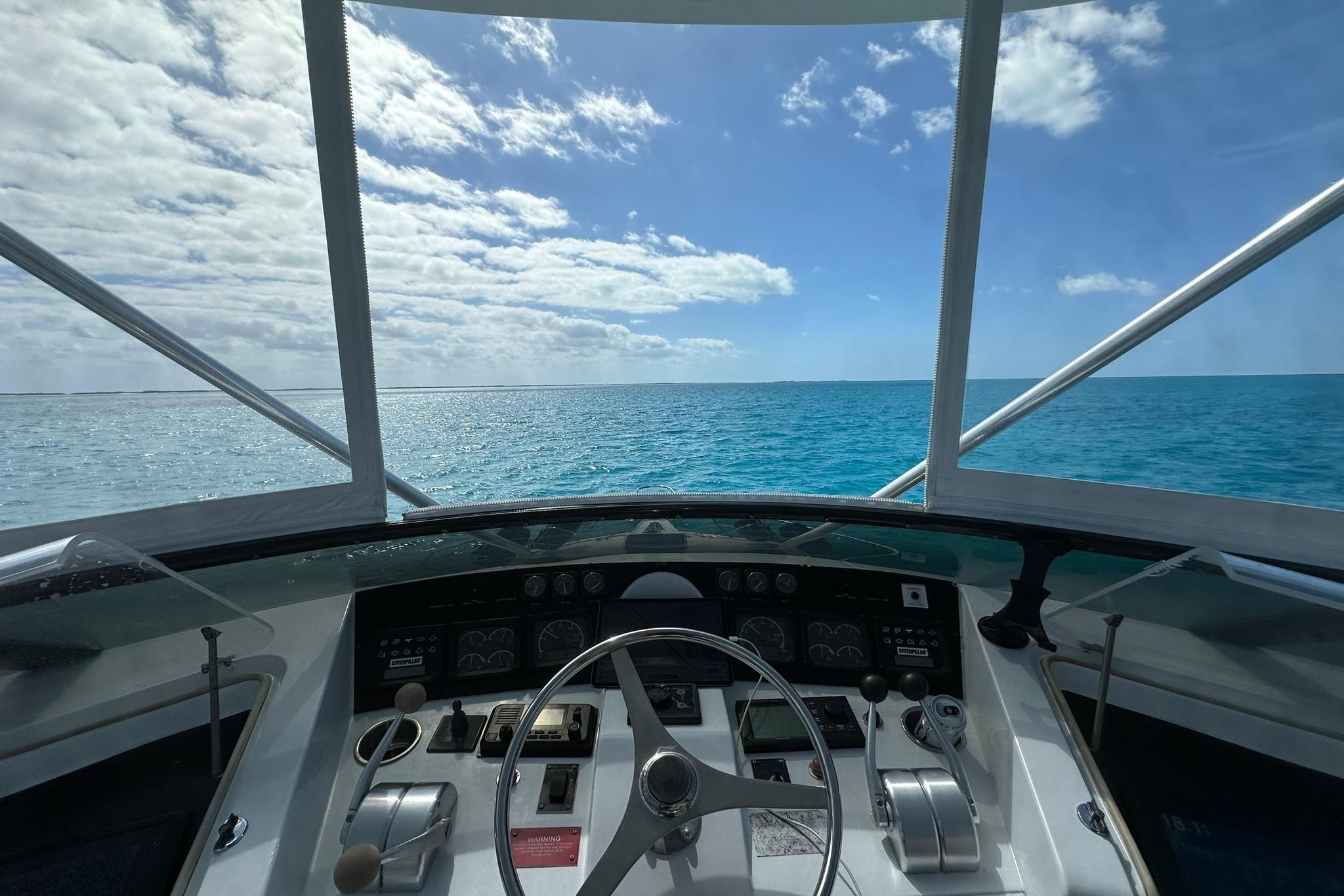 1999 Hatteras 52 Sport Deck Motor Yacht helm with ocean view under blue sky.