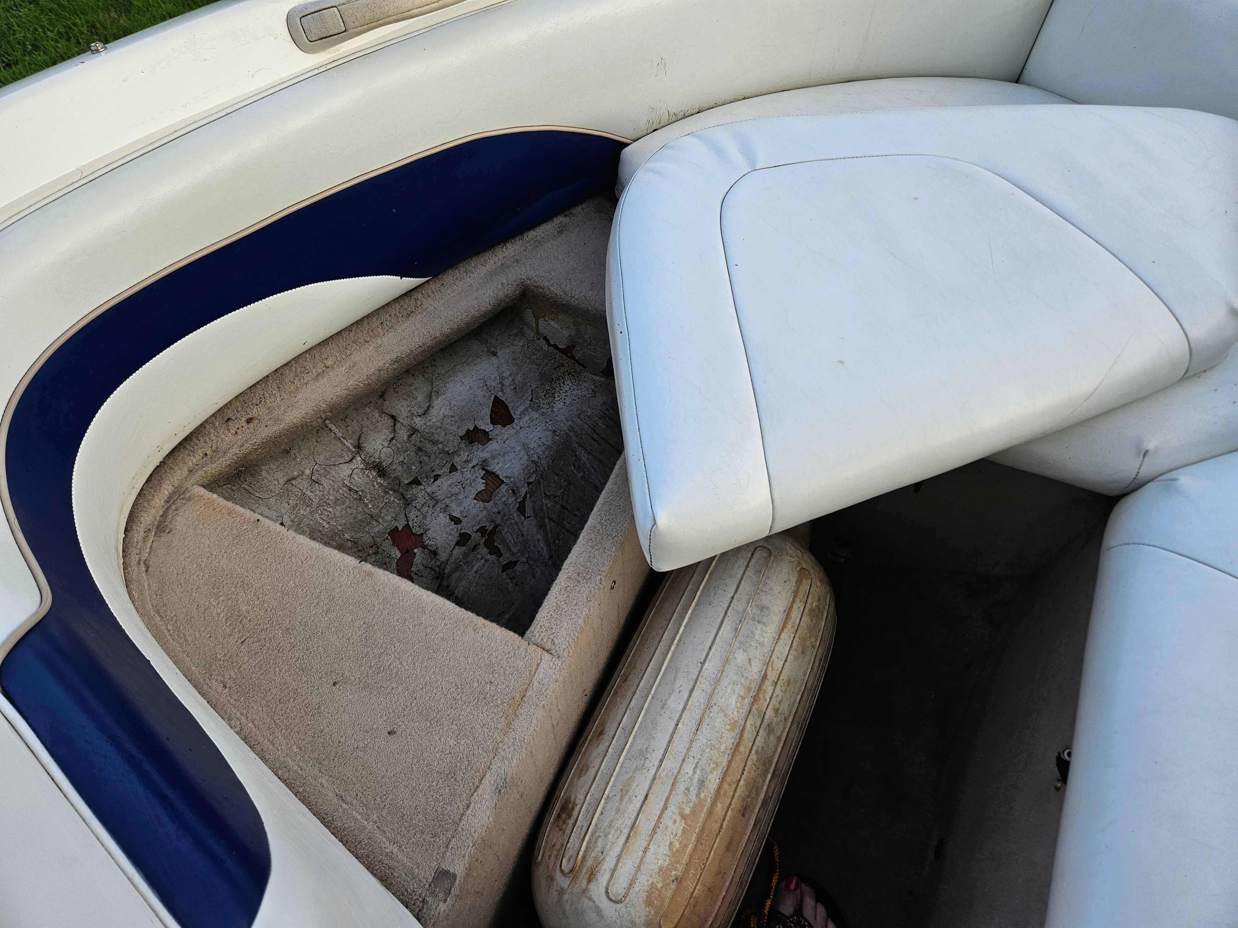Interior of a 1996 Wellcraft Excel with worn upholstery and storage compartment.