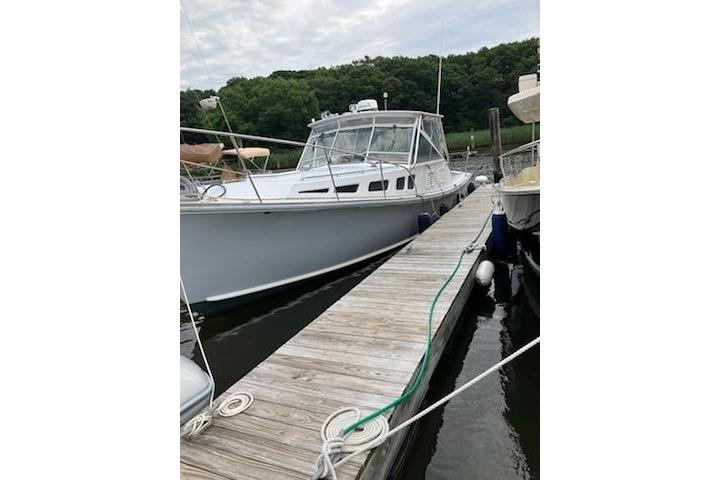 1978 Dyer 40 Express Cruiser docked at a marina with lush greenery.