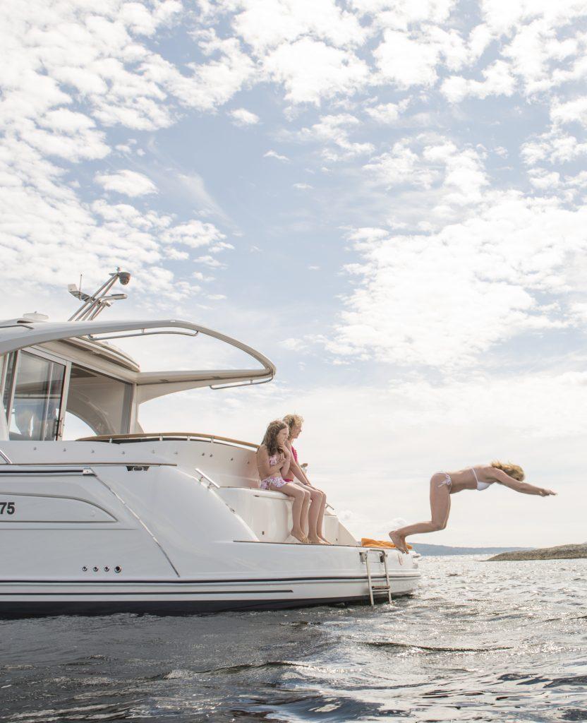 People enjoying a dive from a 2025 Marex 375 yacht under a partly cloudy sky.