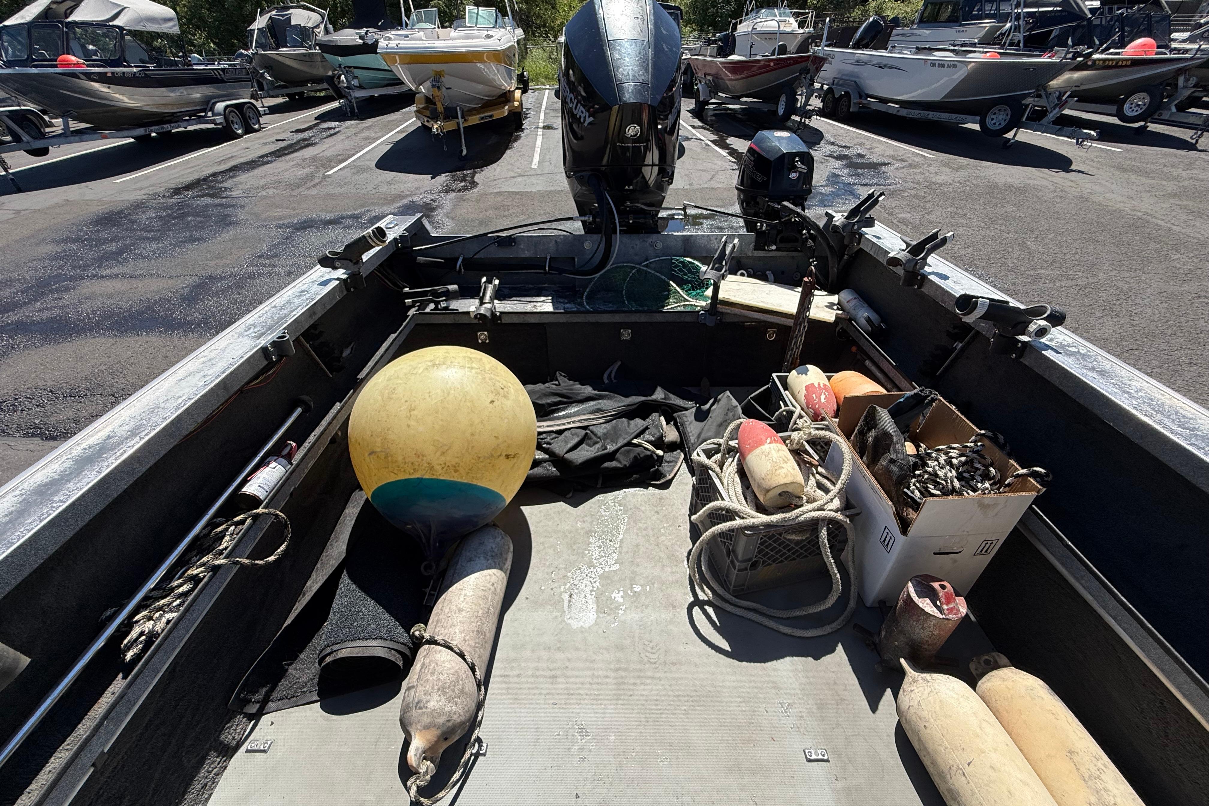 2004 Alumaweld Intruder Outboard 20 boat with fishing gear and buoys in parking lot.