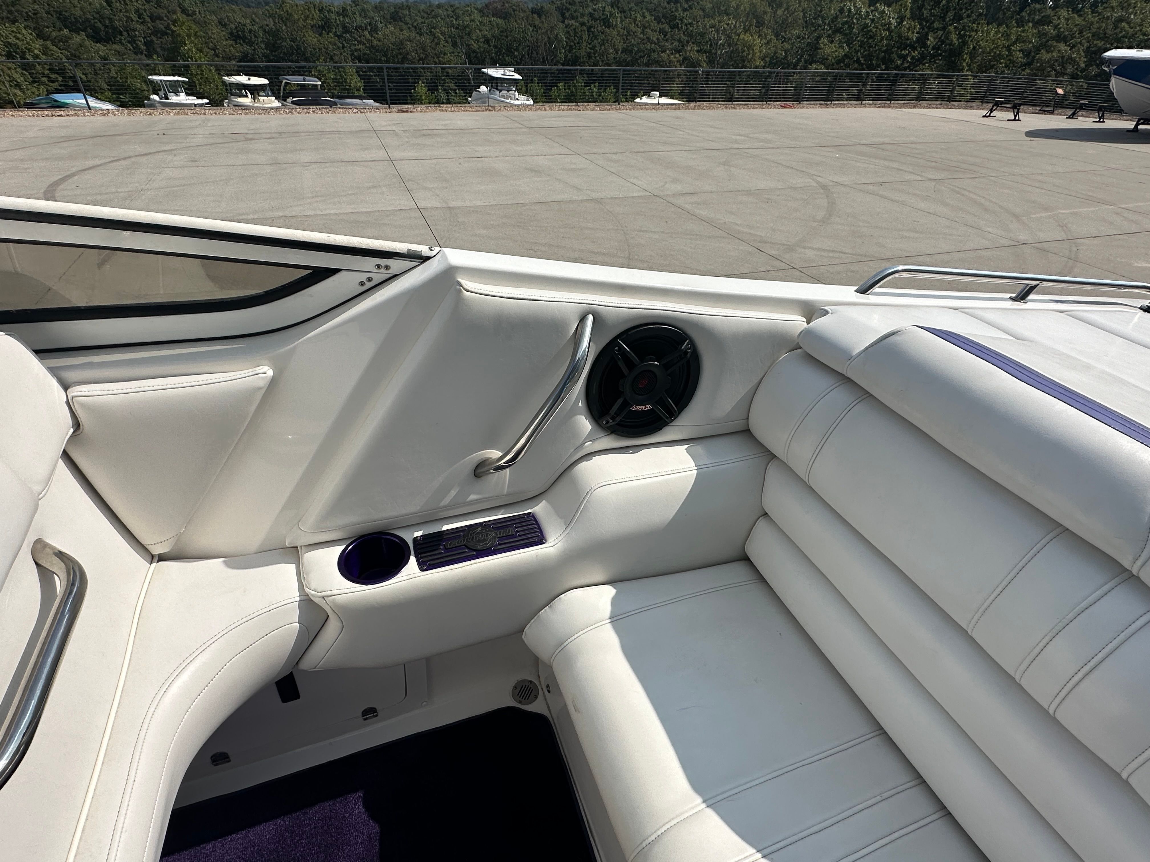 Interior view of a white boat with cushioned seating and a speaker.