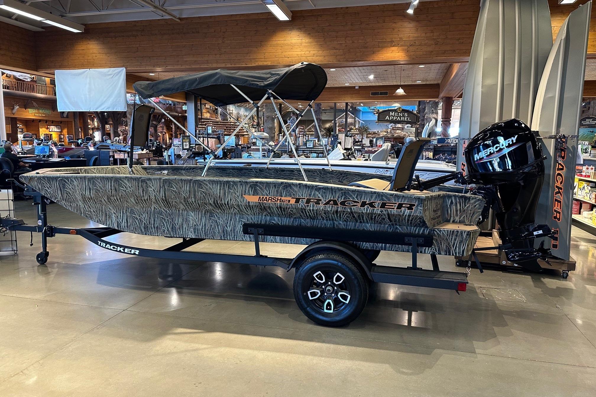 2026 Tracker Grizzly 1756 T Marsh boat displayed indoors with Mercury outboard motor.