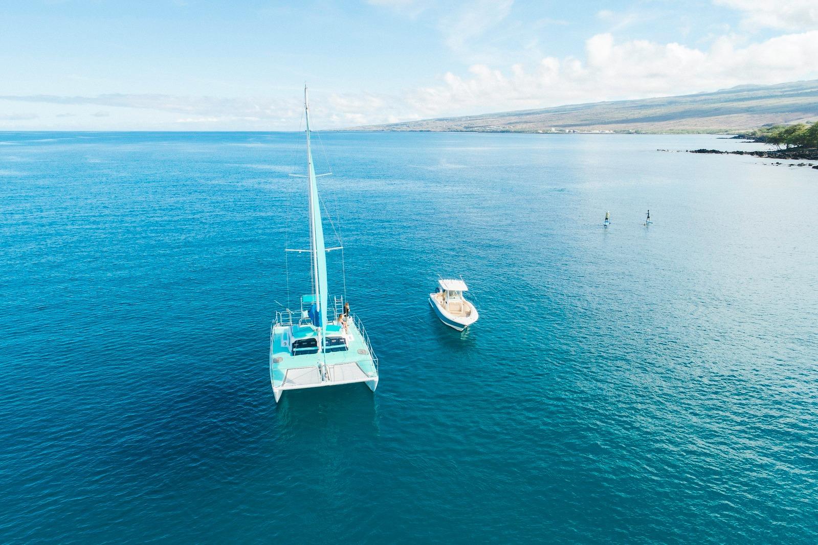 Aerial view of 1978 CSK Beach Catamaran sailing in clear blue ocean waters.
