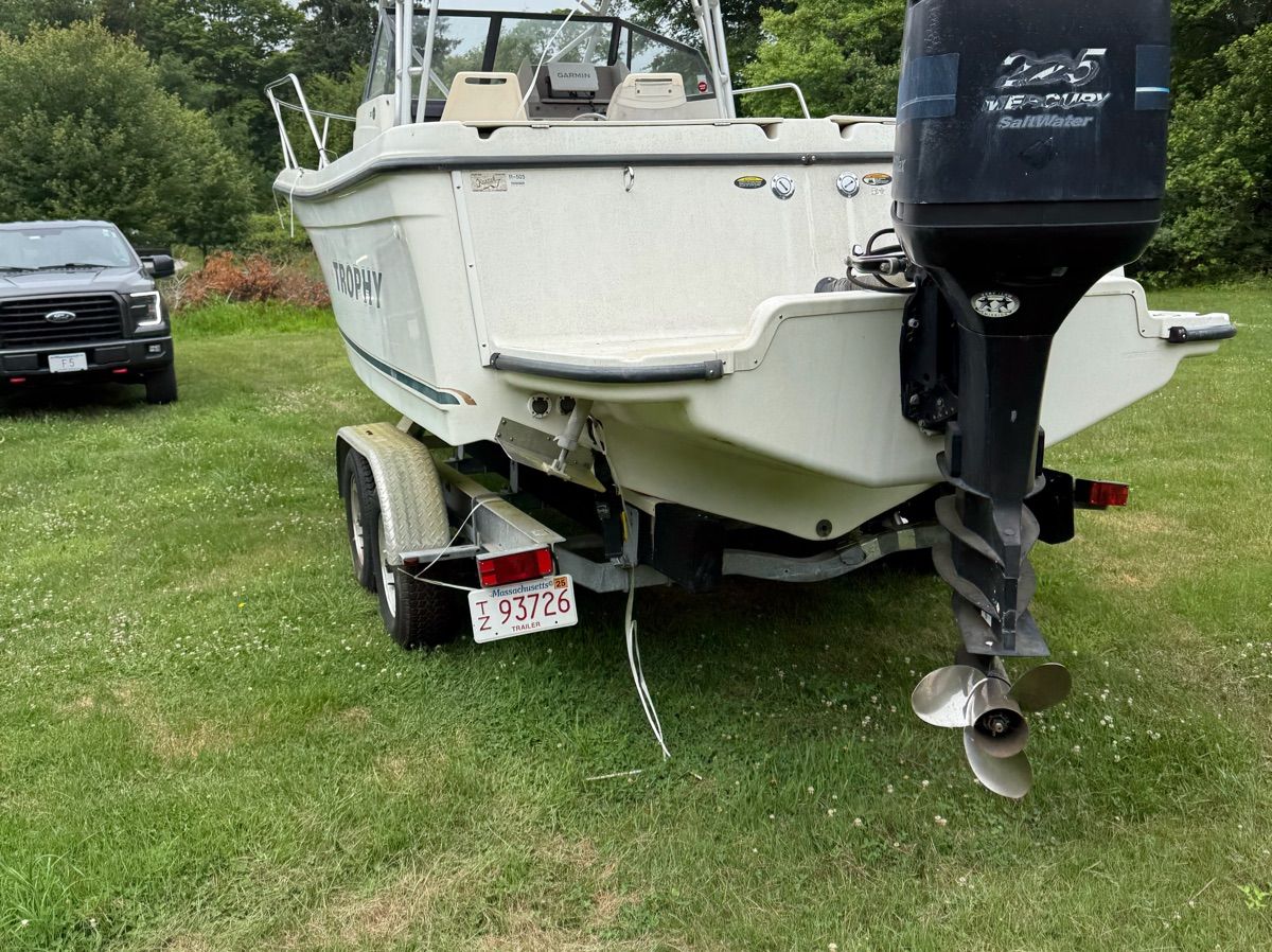 A 2001 Trophy 2509 Walkaround boat on a trailer in a grassy area.