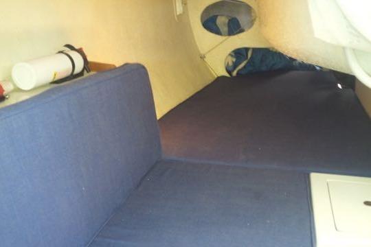 Interior cabin of a 2001 Shock 40 sailboat with blue cushions and storage.