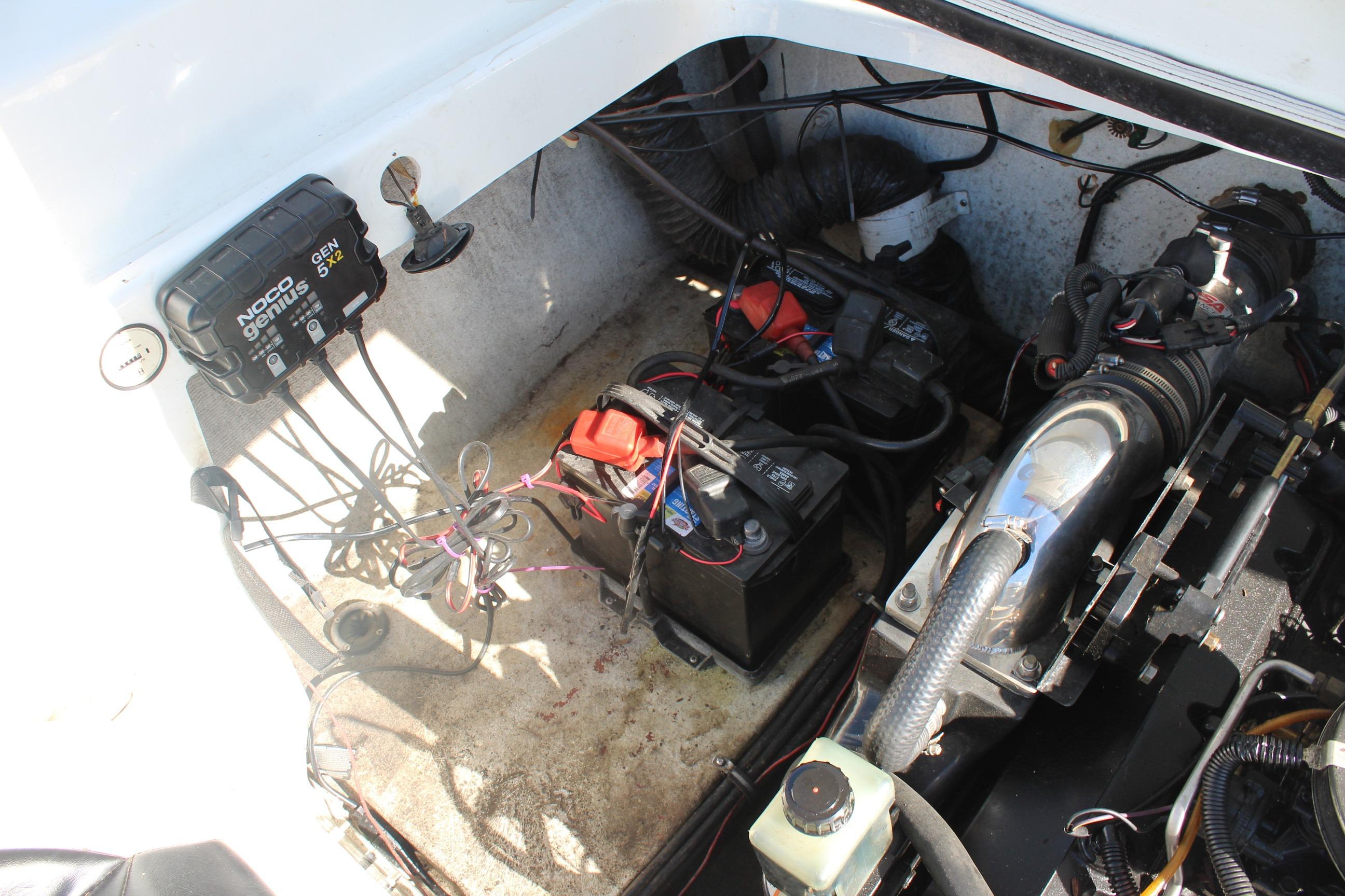 Engine compartment of a 1996 Baja 232 boat with batteries and wiring.