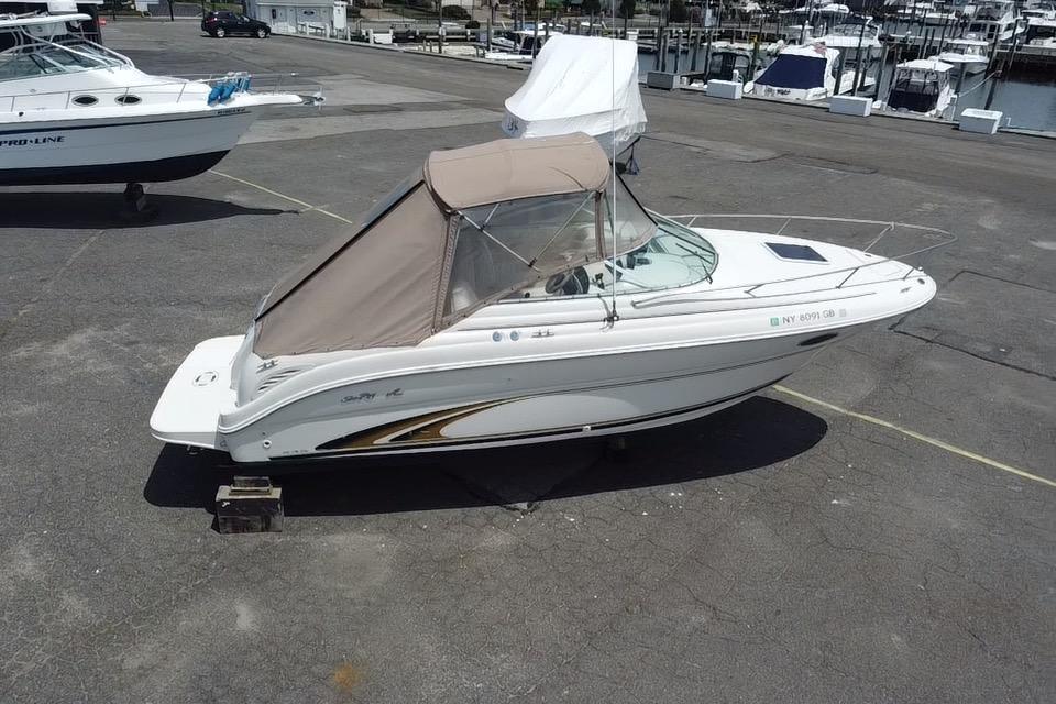 2001 Sea Ray 245 Weekender boat with beige canopy on a marina lot.