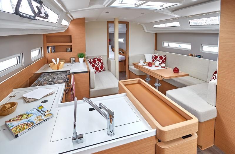 Interior of 2025 Jeanneau Sun Odyssey 410 yacht, featuring modern kitchen and cozy seating area.