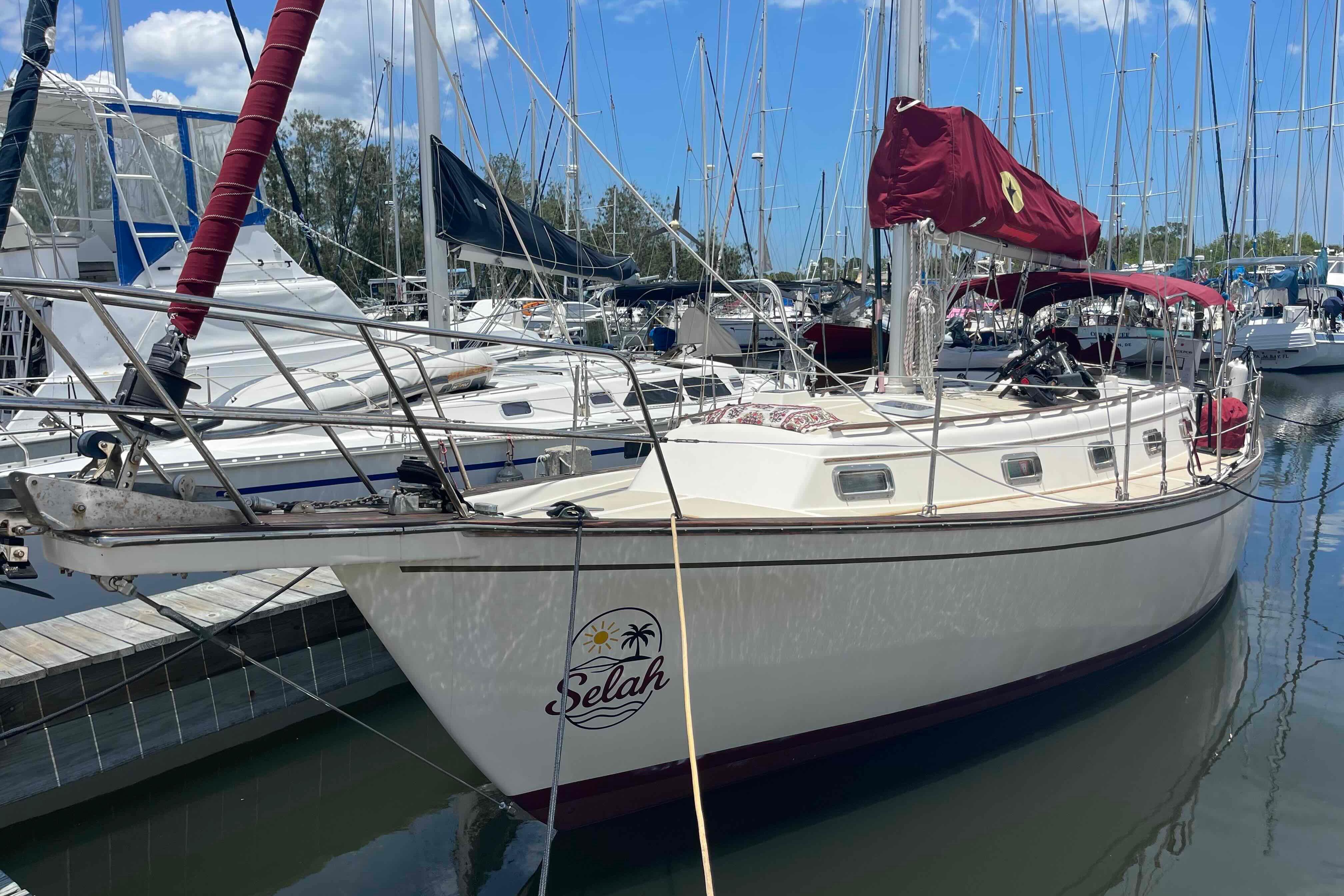 1989 Island Packet 35 sailboat docked in a marina, featuring a red sail cover.
