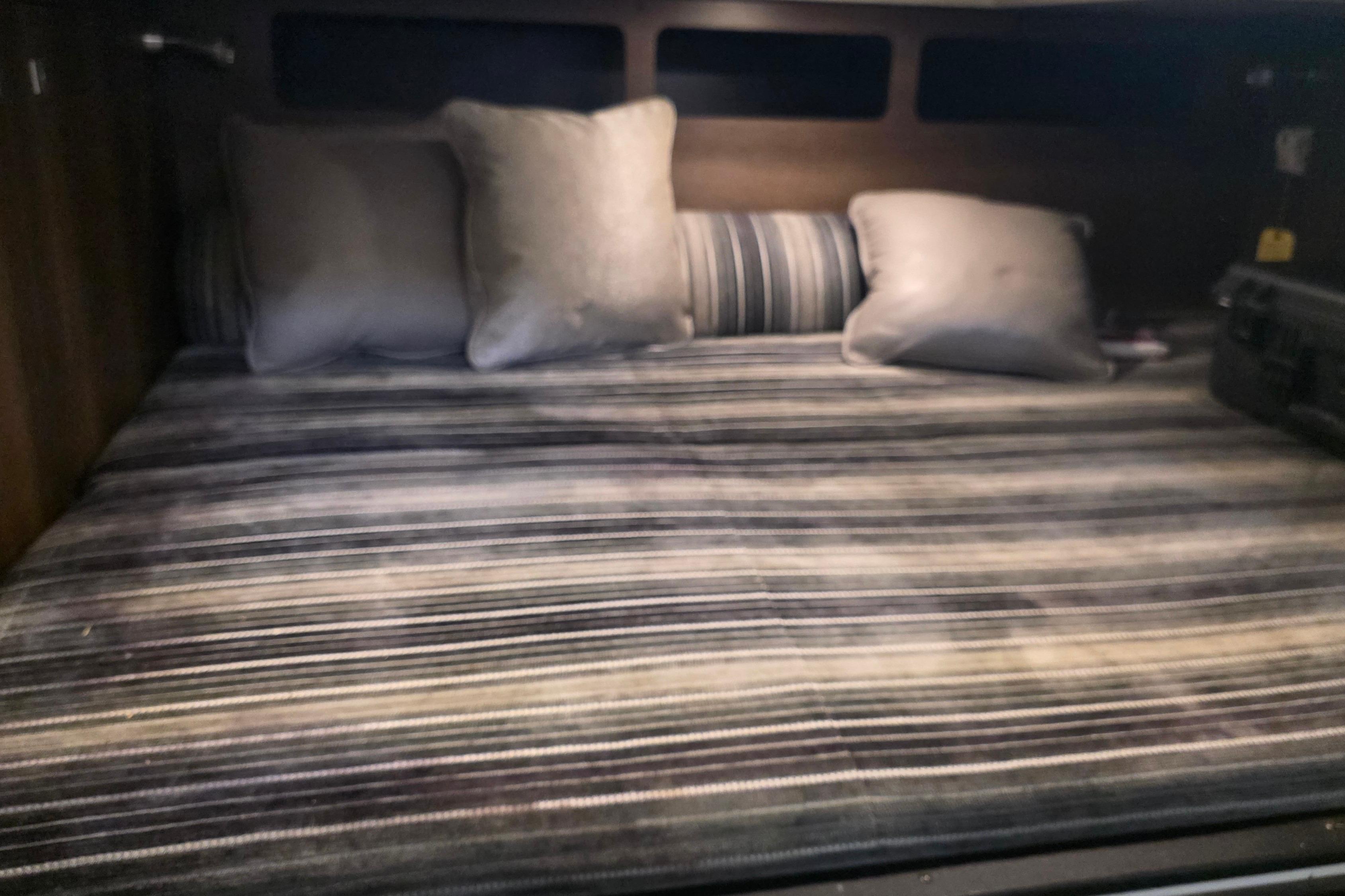 Cozy bed with striped bedding in 2017 Monterey 360 Sport Coupe cabin.