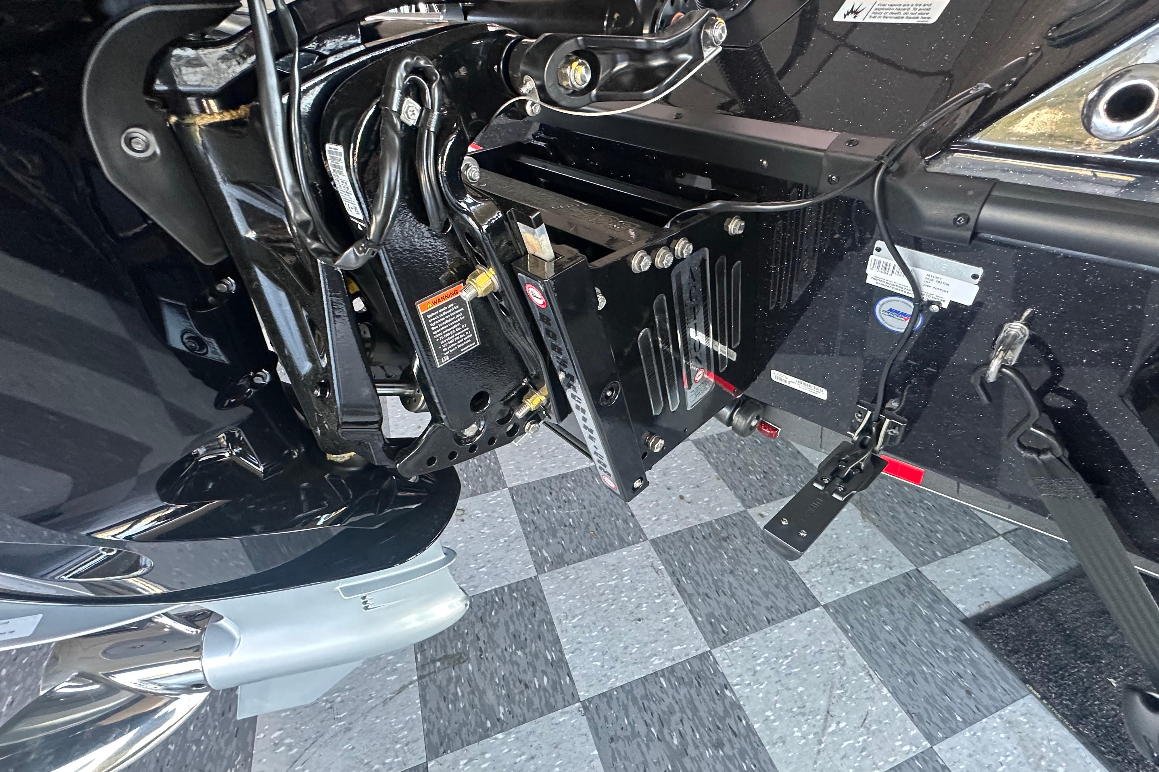 Close-up of 2026 Triton 20XP Patriot boat engine mount on checkered floor.