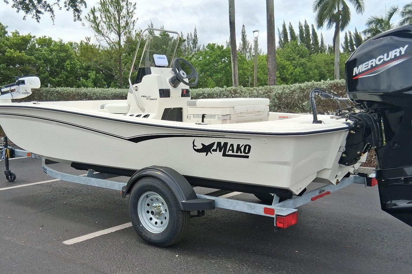 2026 Mako Pro Skiff 15 CC boat on trailer with Mercury engine in parking lot.