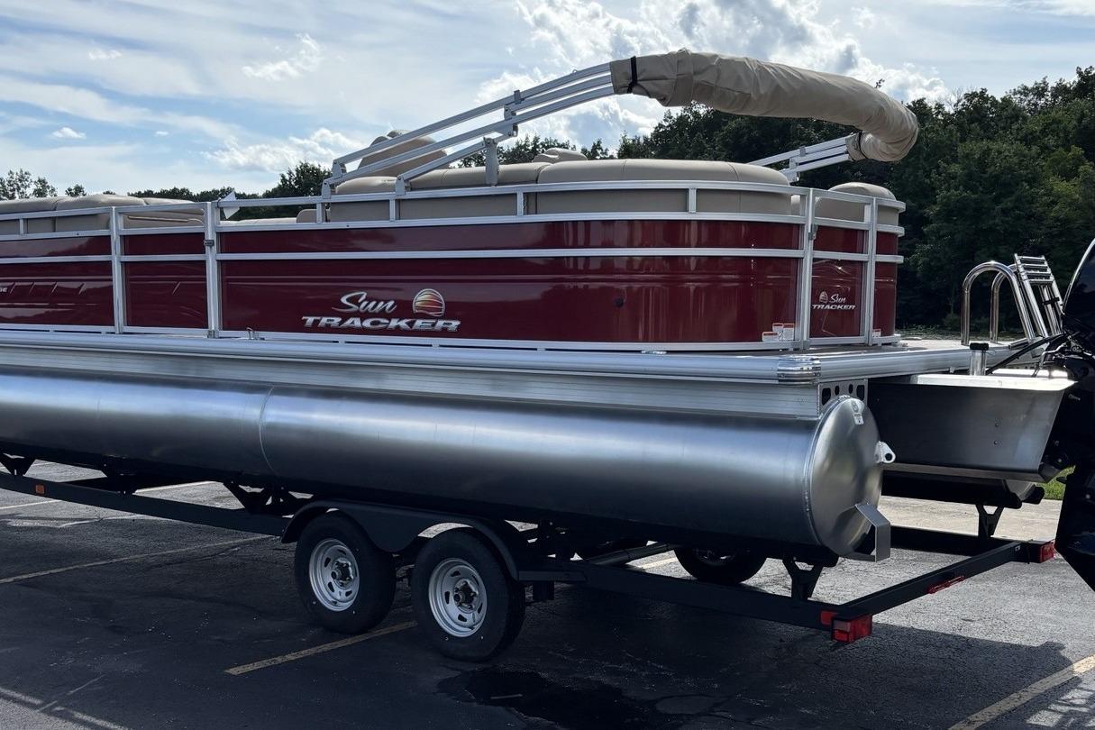 2024 Sun Tracker Party Barge 24 DLX pontoon boat on trailer, parked outdoors.