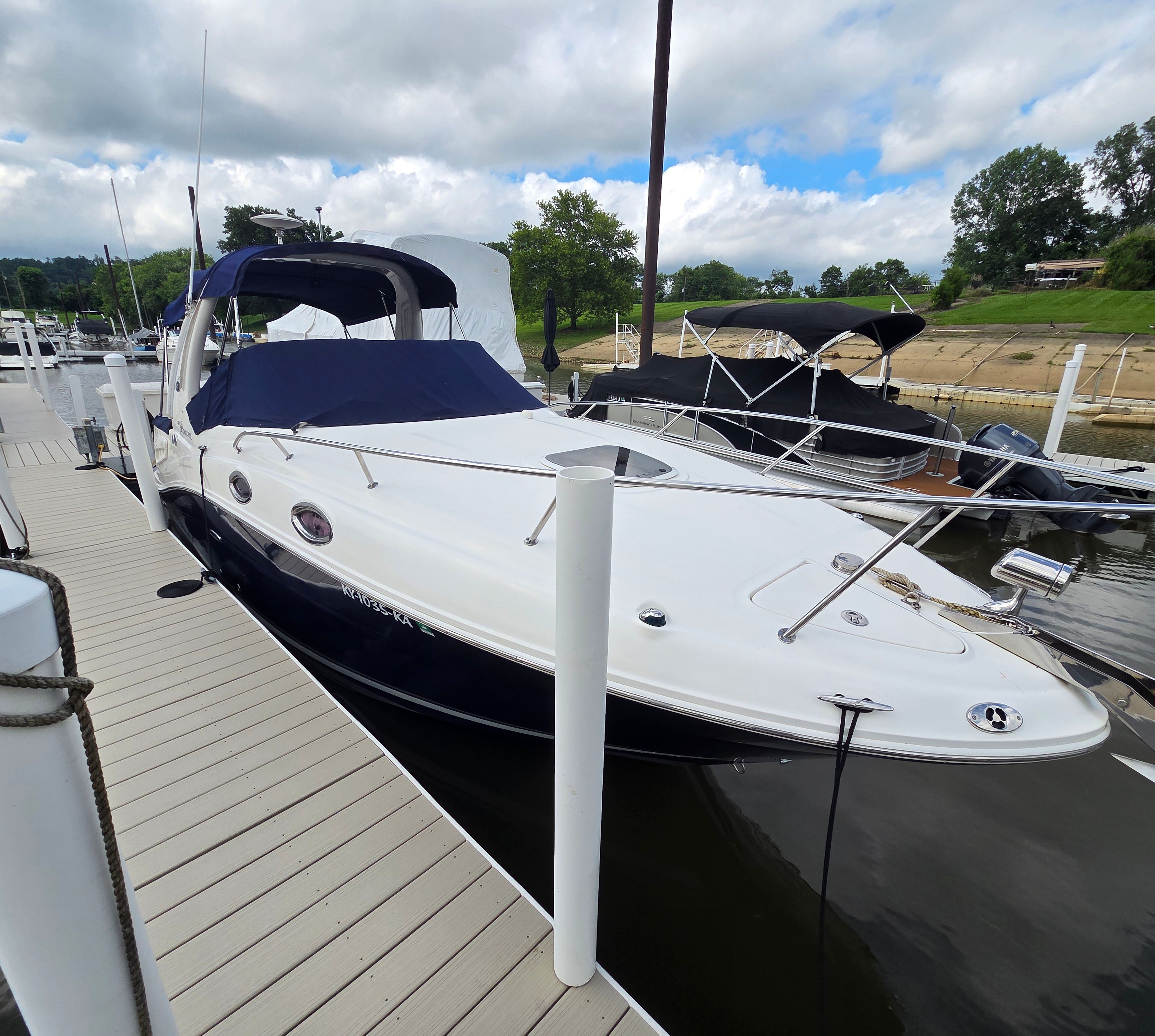 A 2005 Sea Ray Sundancer 260 docked, featuring a blue canopy.