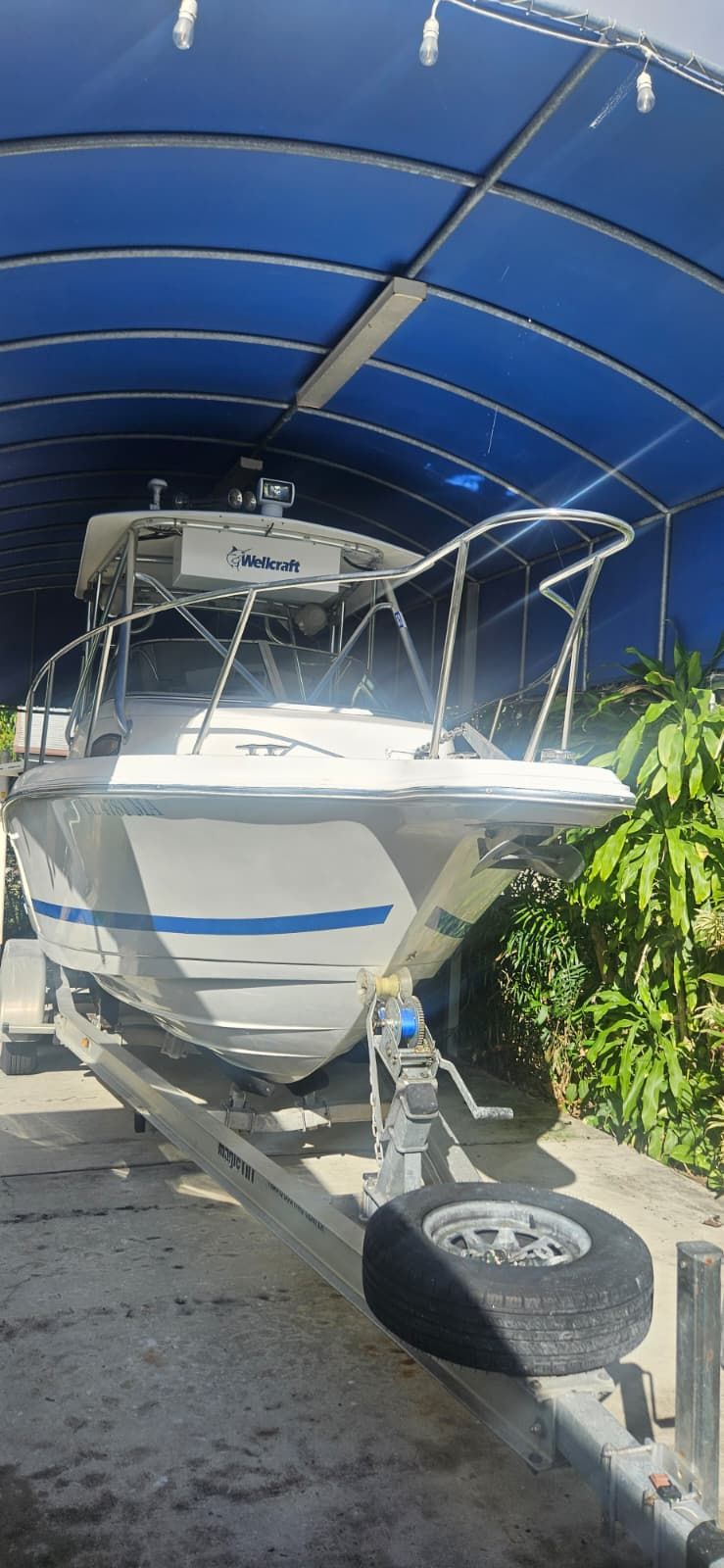 2000 Wellcraft 24 Walkaround boat on trailer under blue canopy.