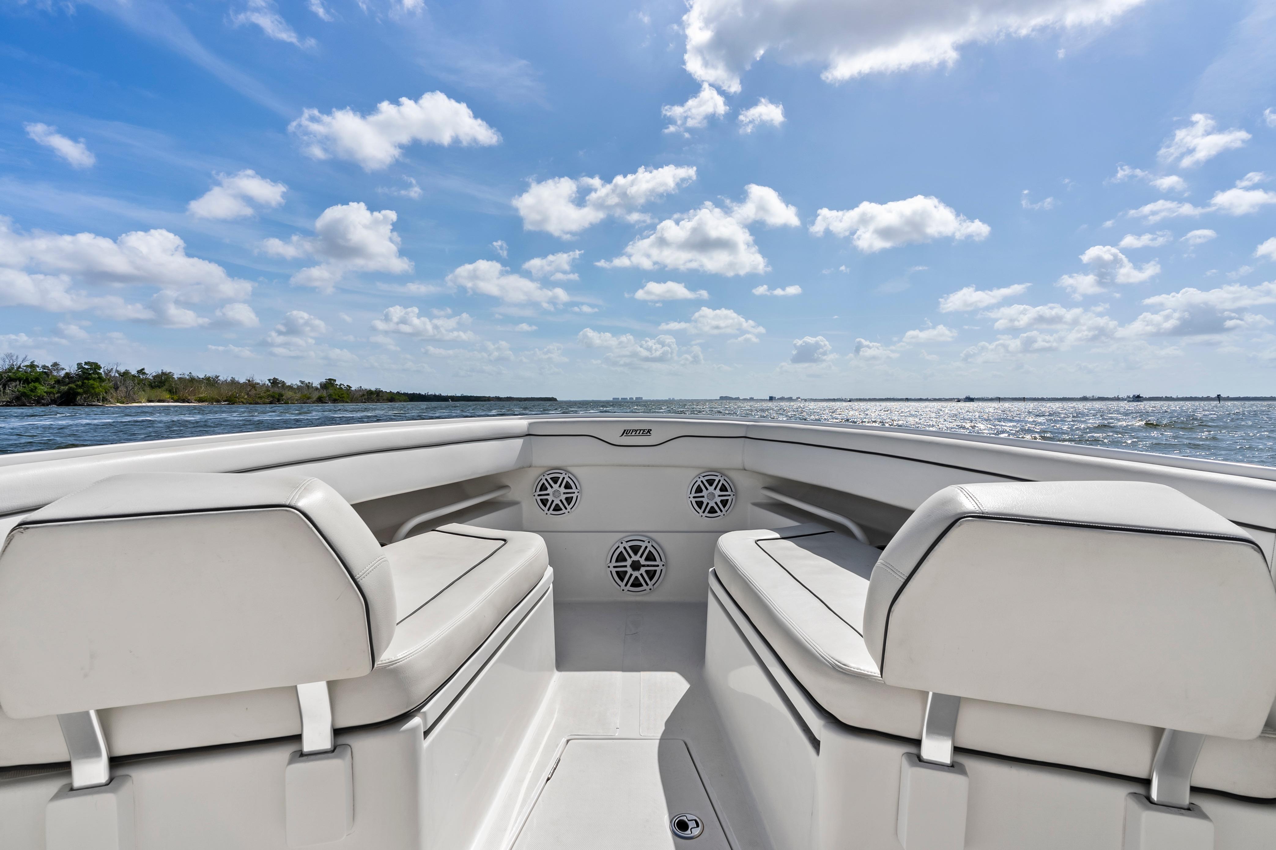 2015 Jupiter 34 HFS boat interior with white seating, ocean view, and blue sky.