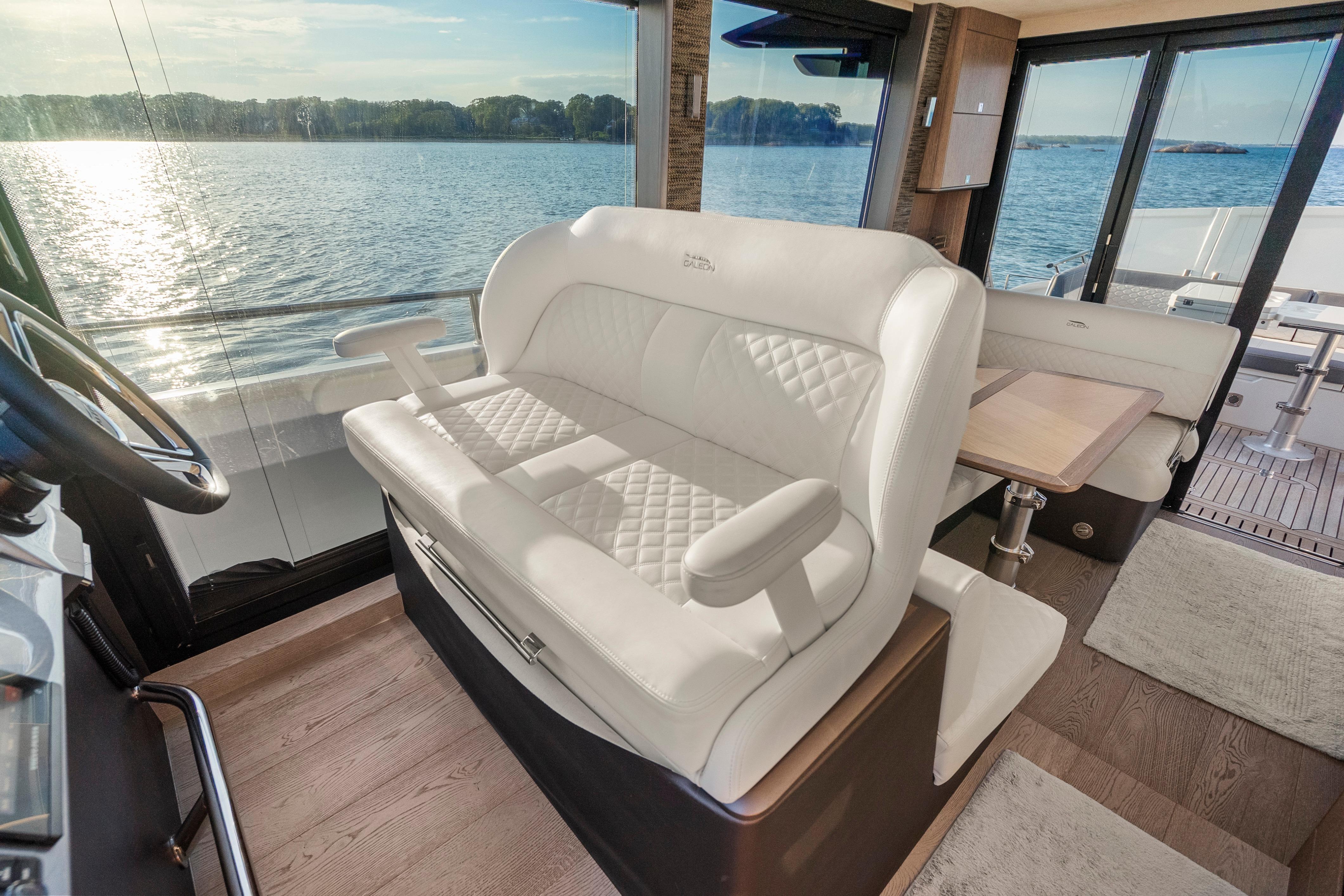 Luxurious interior of 2023 Galeon 400 Fly yacht with white seating and scenic water view.