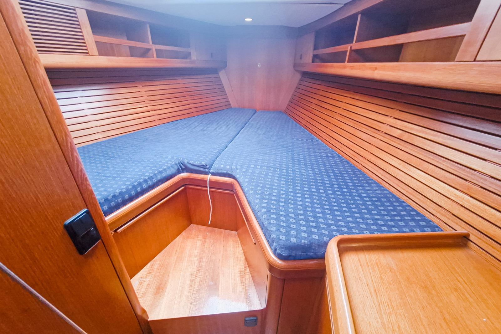 Cozy cabin interior of 2002 Nautor Swan 44 yacht with wooden finish and blue cushions.