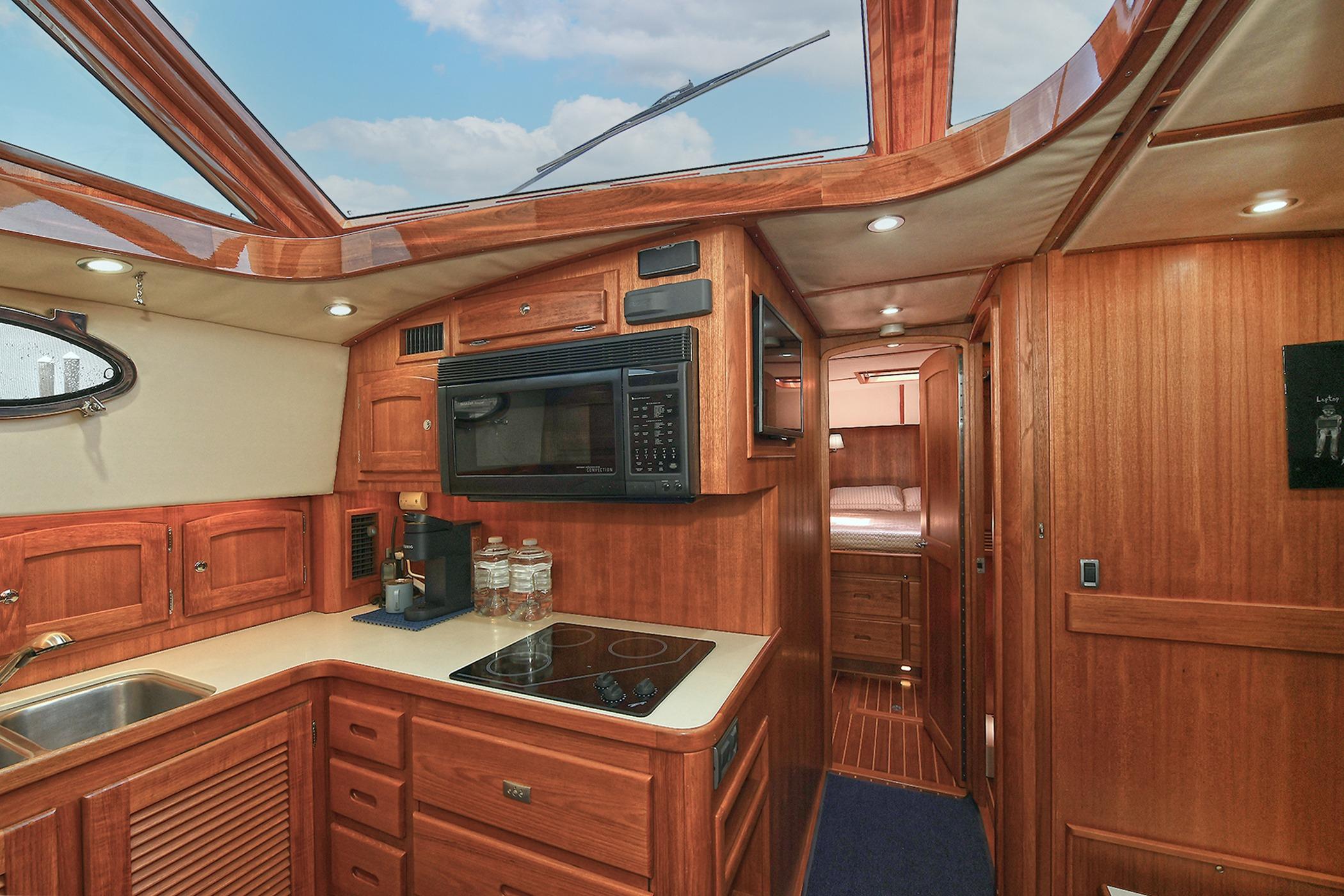 Luxurious 2005 San Juan Downeast Express yacht interior with wood cabinetry and modern kitchen amenities.